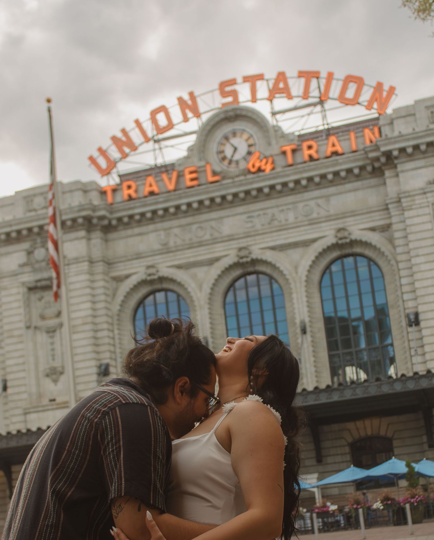 A romantic kiss shared in front of Denver's Union Station's iconic orange signage.