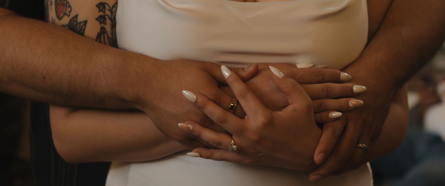 Close-up of hands clasped together against a dark background showing unity and connection.