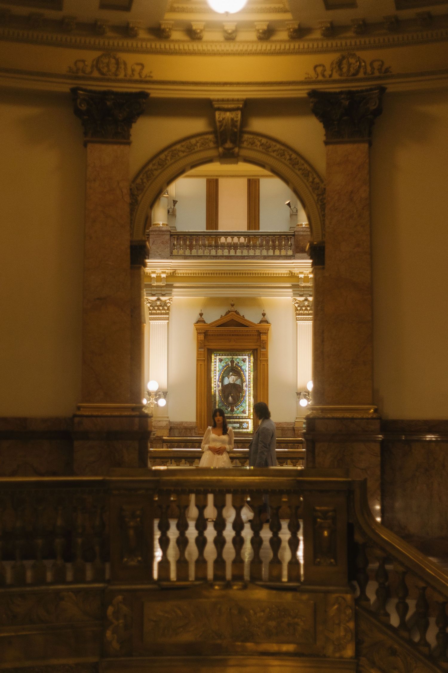 Elegant marble staircase and ornate architectural details in historic building interior with warm lighting and golden tones.