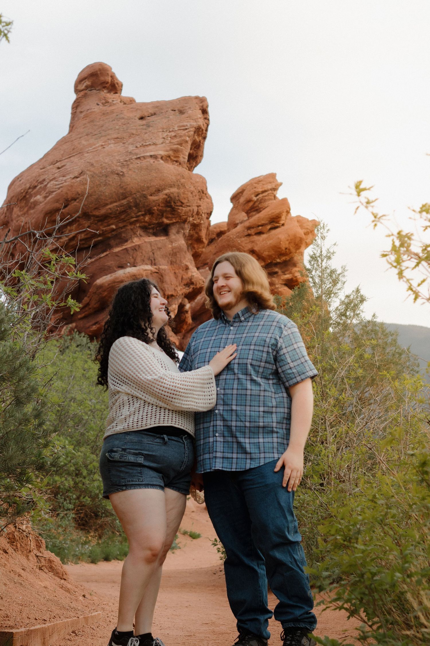 Romantic moment captured against stunning red rock formations and desert vegetation.