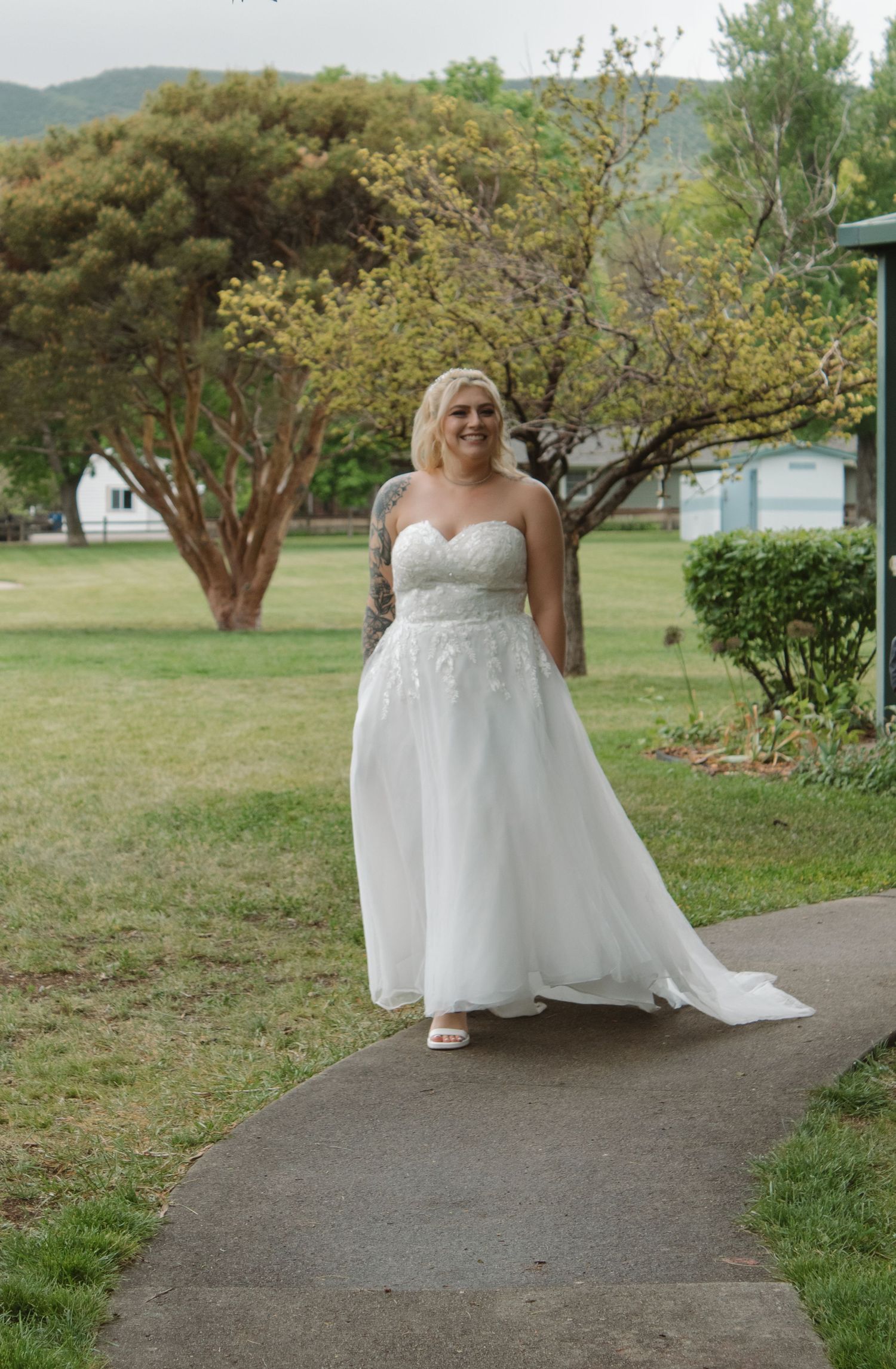 White wedding dress flowing along outdoor pathway surrounded by spring greenery.