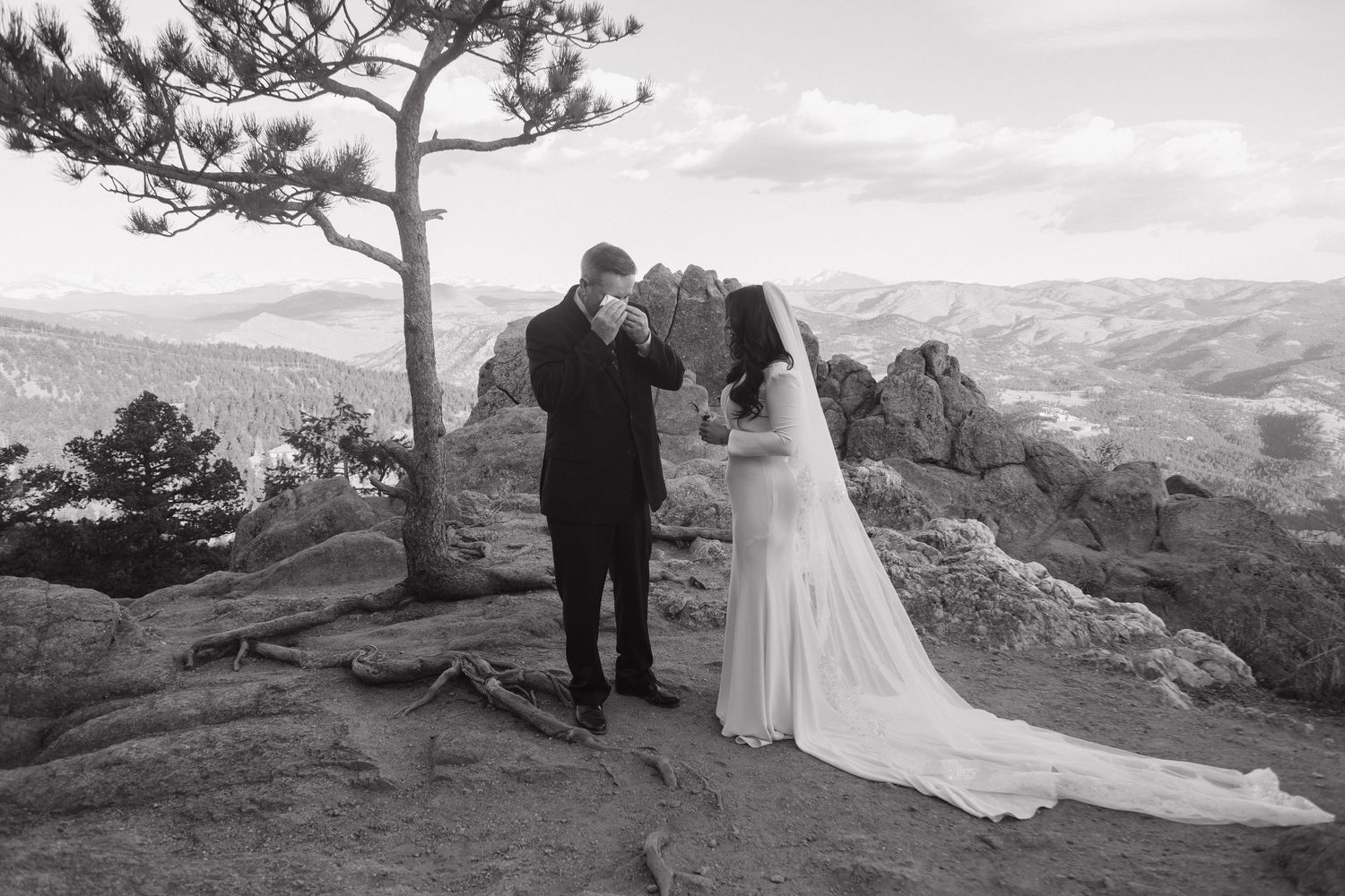Bride and groom sharing an emotional first look moment on a rocky mountain summit in black and white.