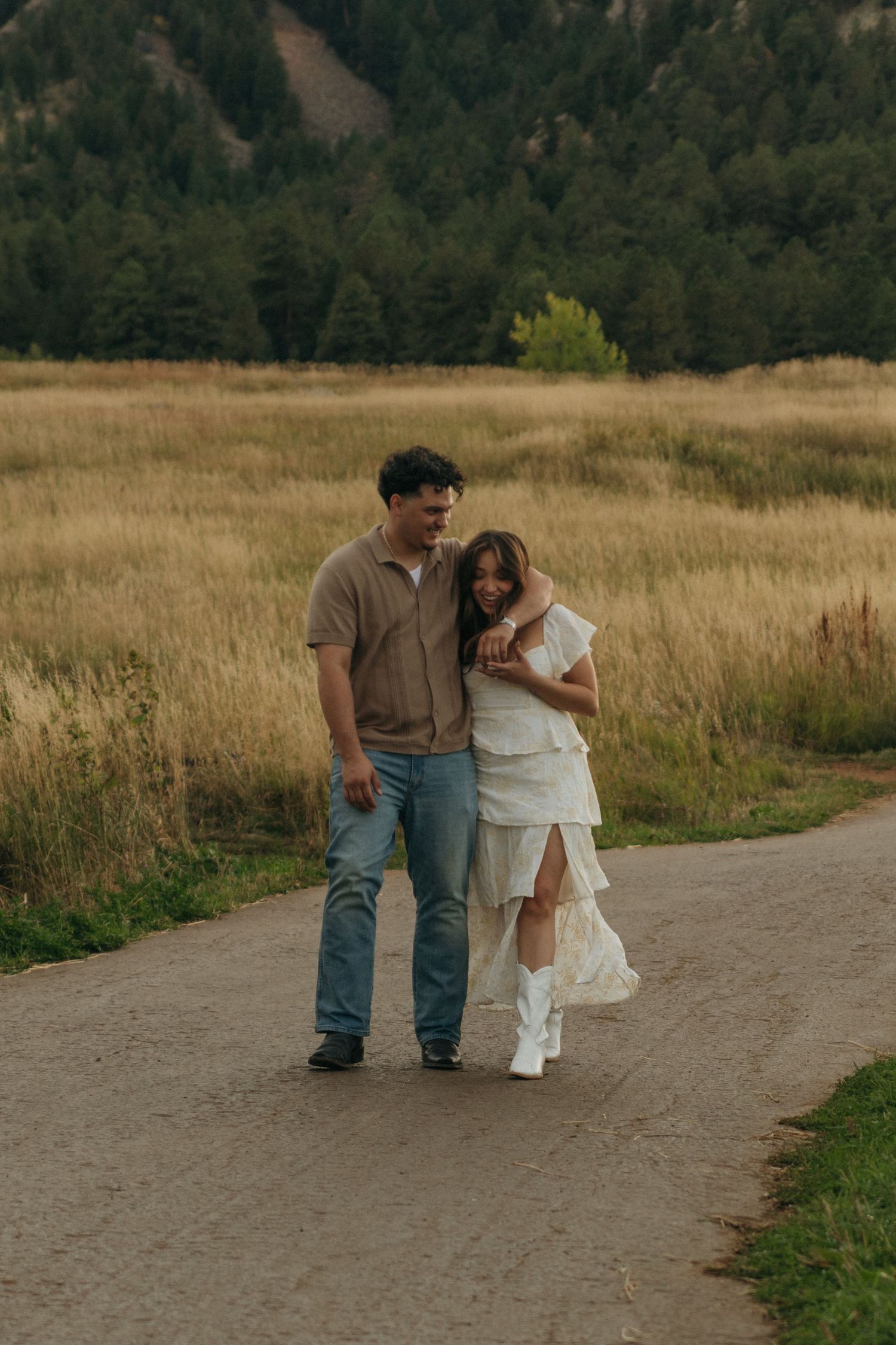 Couple walking together on a path through a scenic mountain meadow.