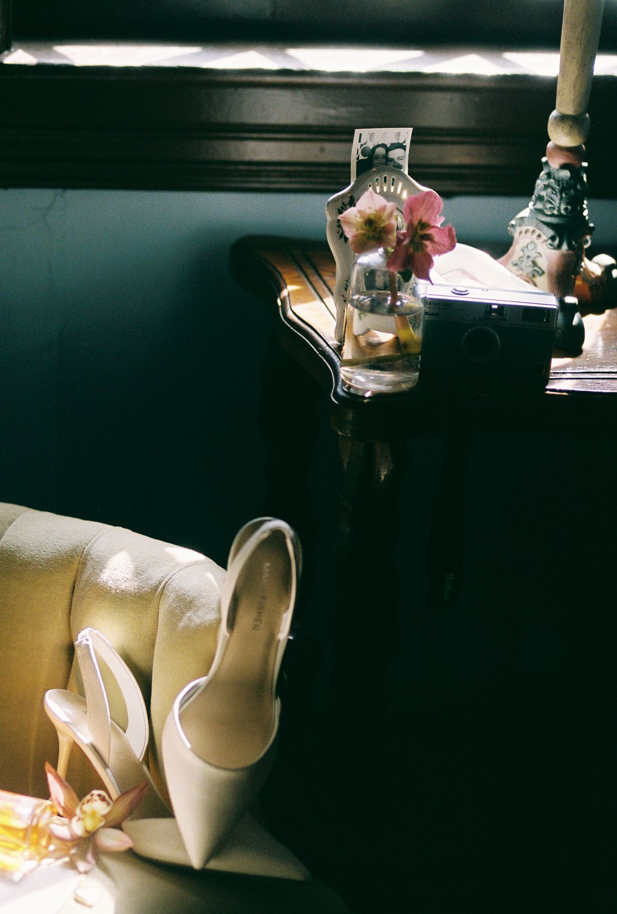 Sunlight casts dramatic shadows on white ceramic objects and furniture in a moody interior setting.