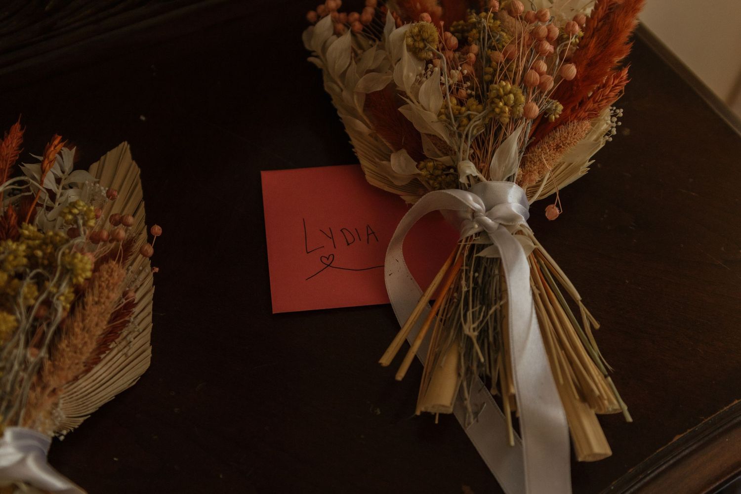 An assortment of dried floral bouquets with white ribbon ties displayed against a dark background.