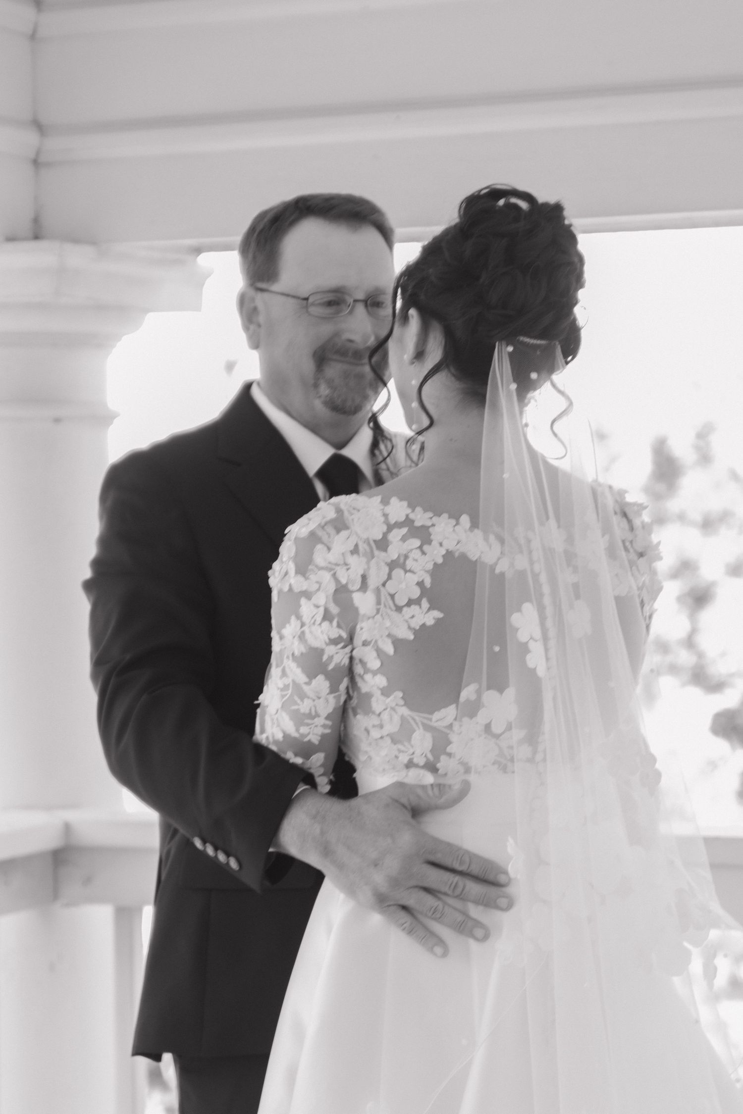 A black and white portrait of a tender moment during a wedding celebration.