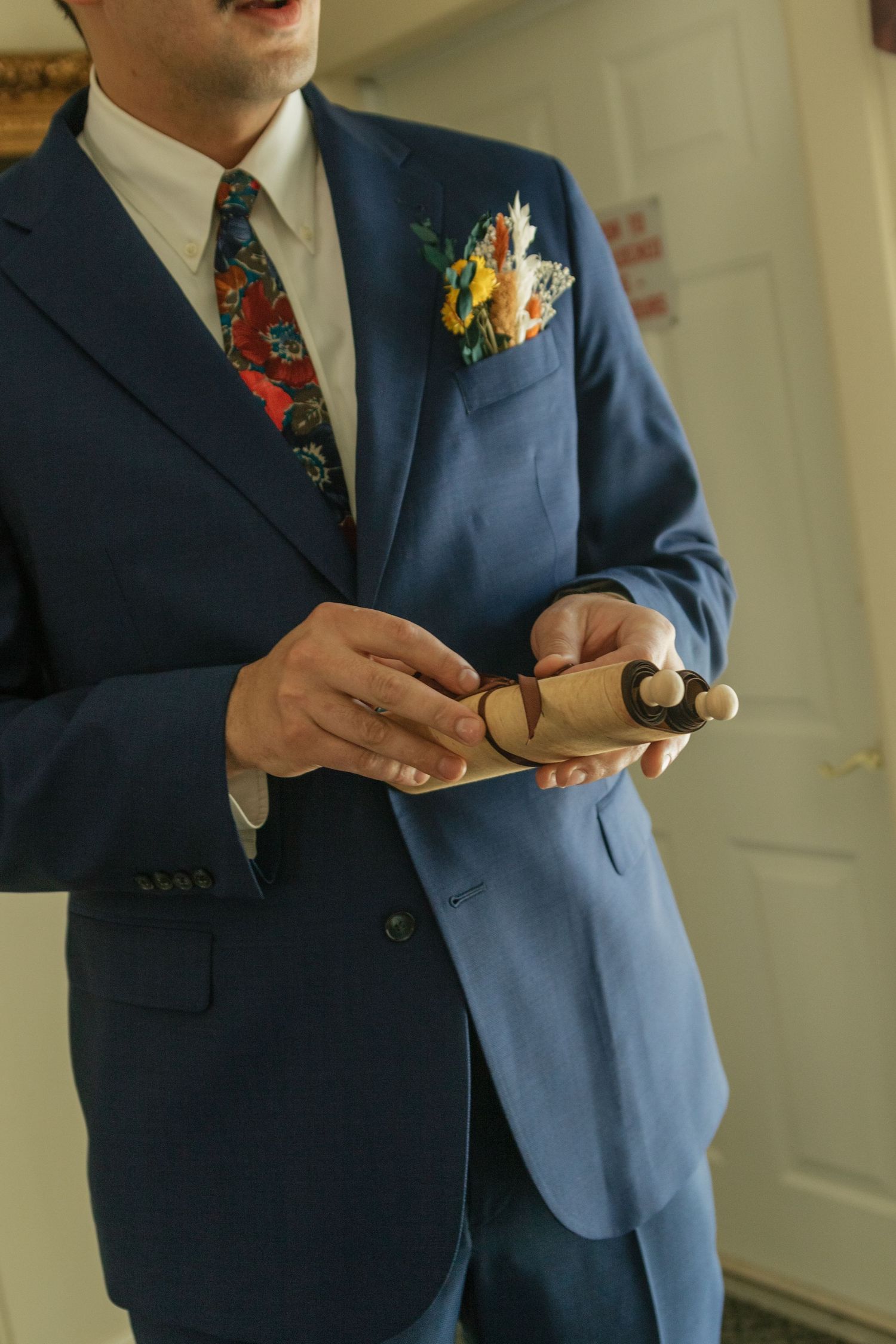 Close-up shots of someone in a navy suit holding and adjusting items for a formal occasion.