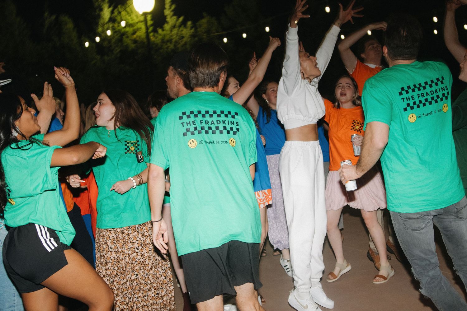 Nighttime outdoor celebration with guests dancing under string lights.