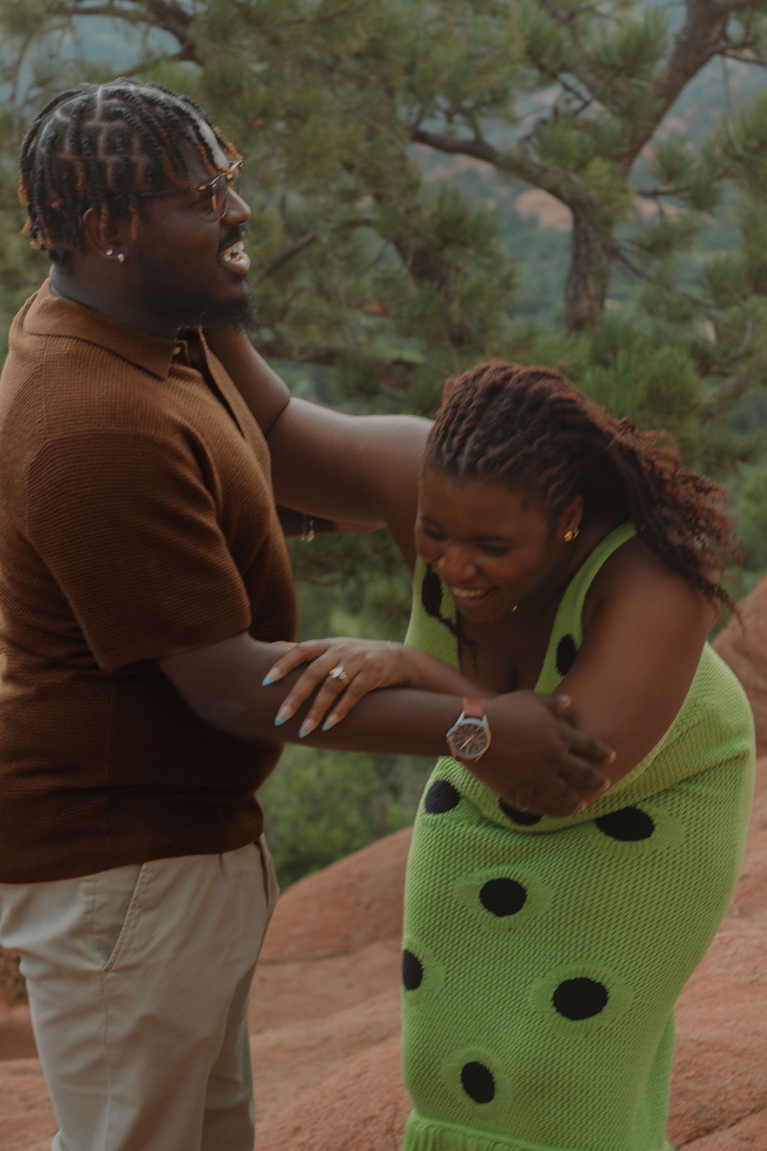 Candid moment of laughter on red rocks during engagement photo session.