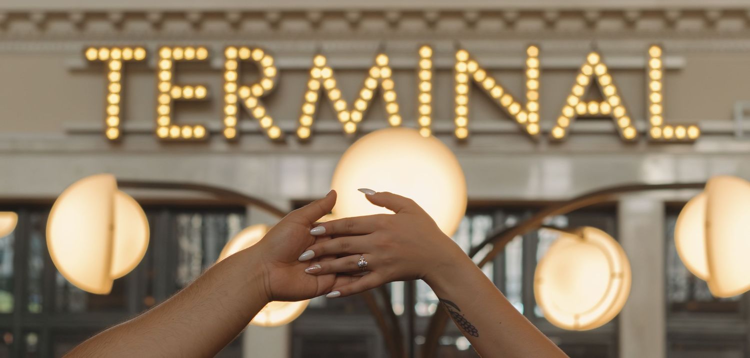 Illuminated 'TERMINAL' sign with glowing light bulbs mounted on a building facade at dusk.