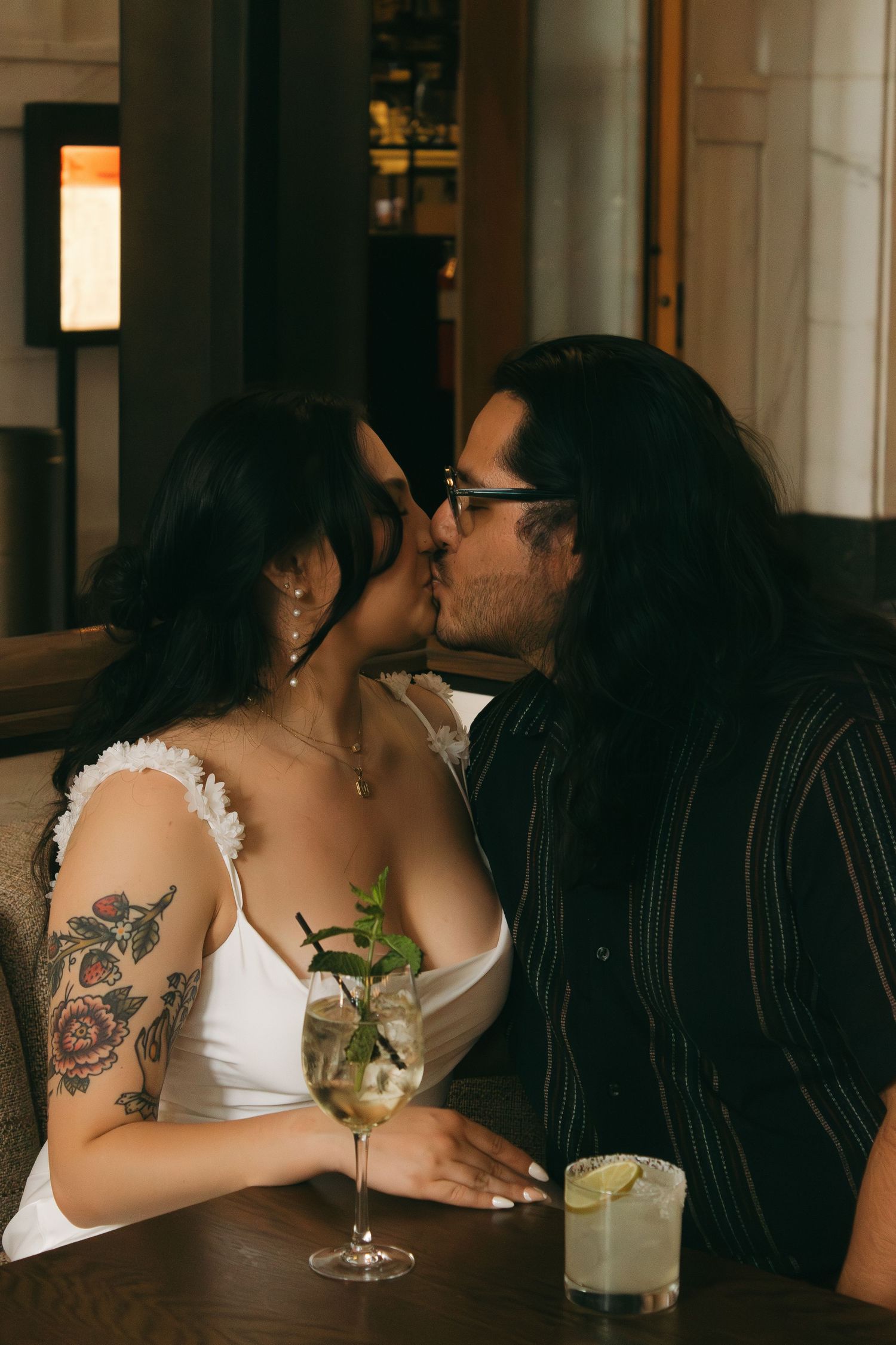 A moody indoor scene with drinks and intimate moments at a dimly lit bar setting.