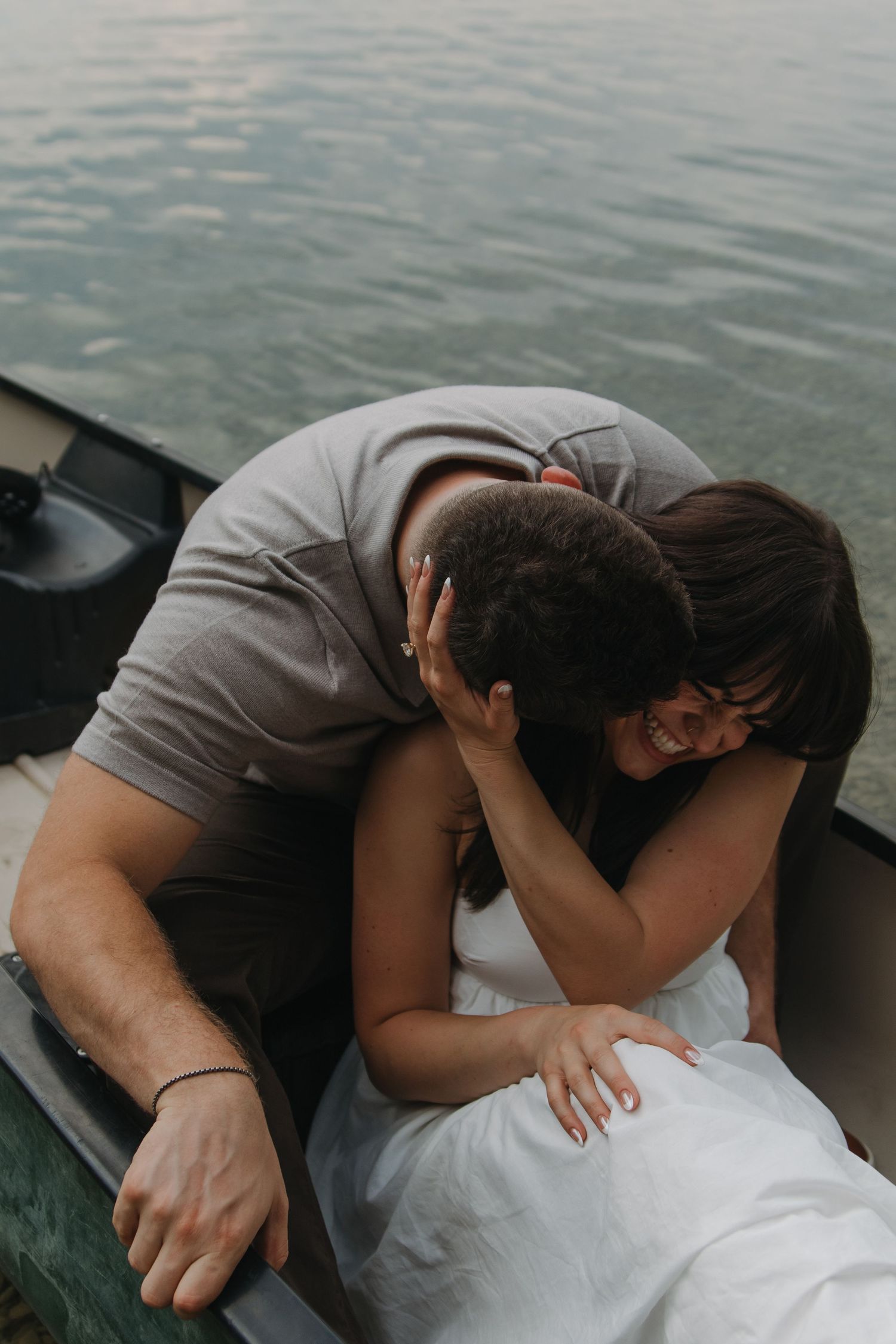 Close-up shot of couple in romantic embrace while sitting in canoe on peaceful waters.