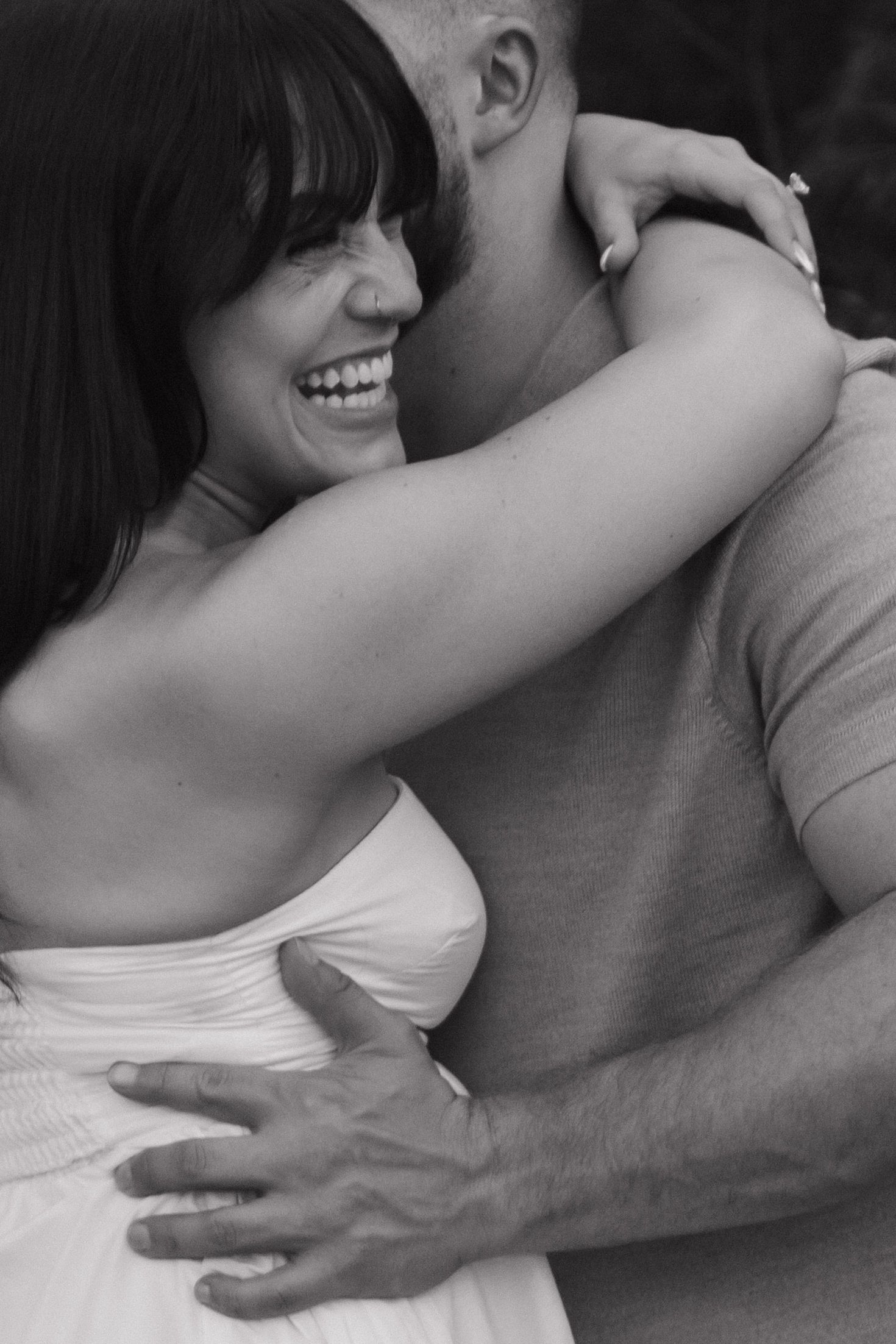 Black and white photo capturing tender embraces between a couple.