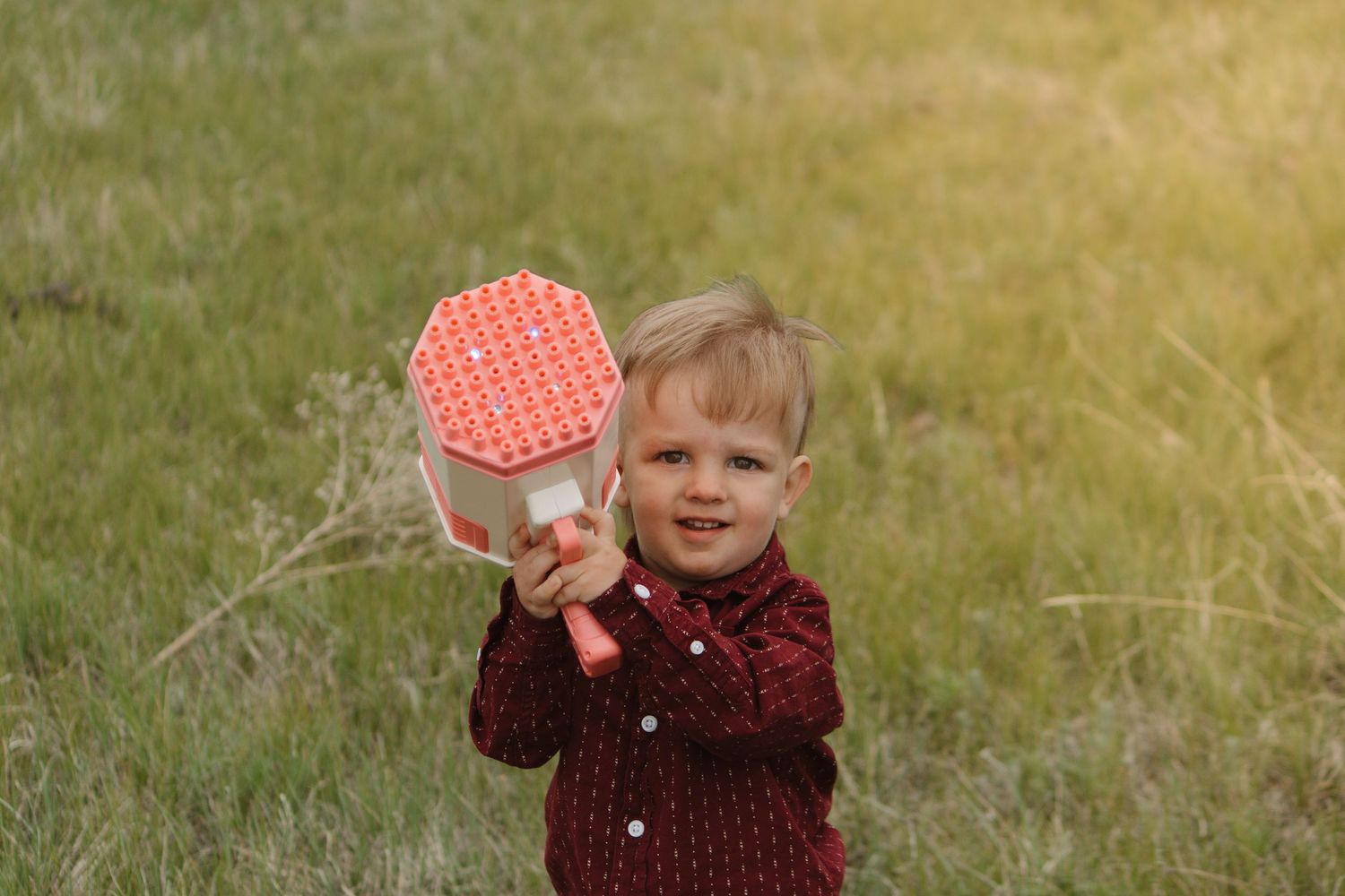Child in red shirt holds up a polka dot heart against golden sunset light.