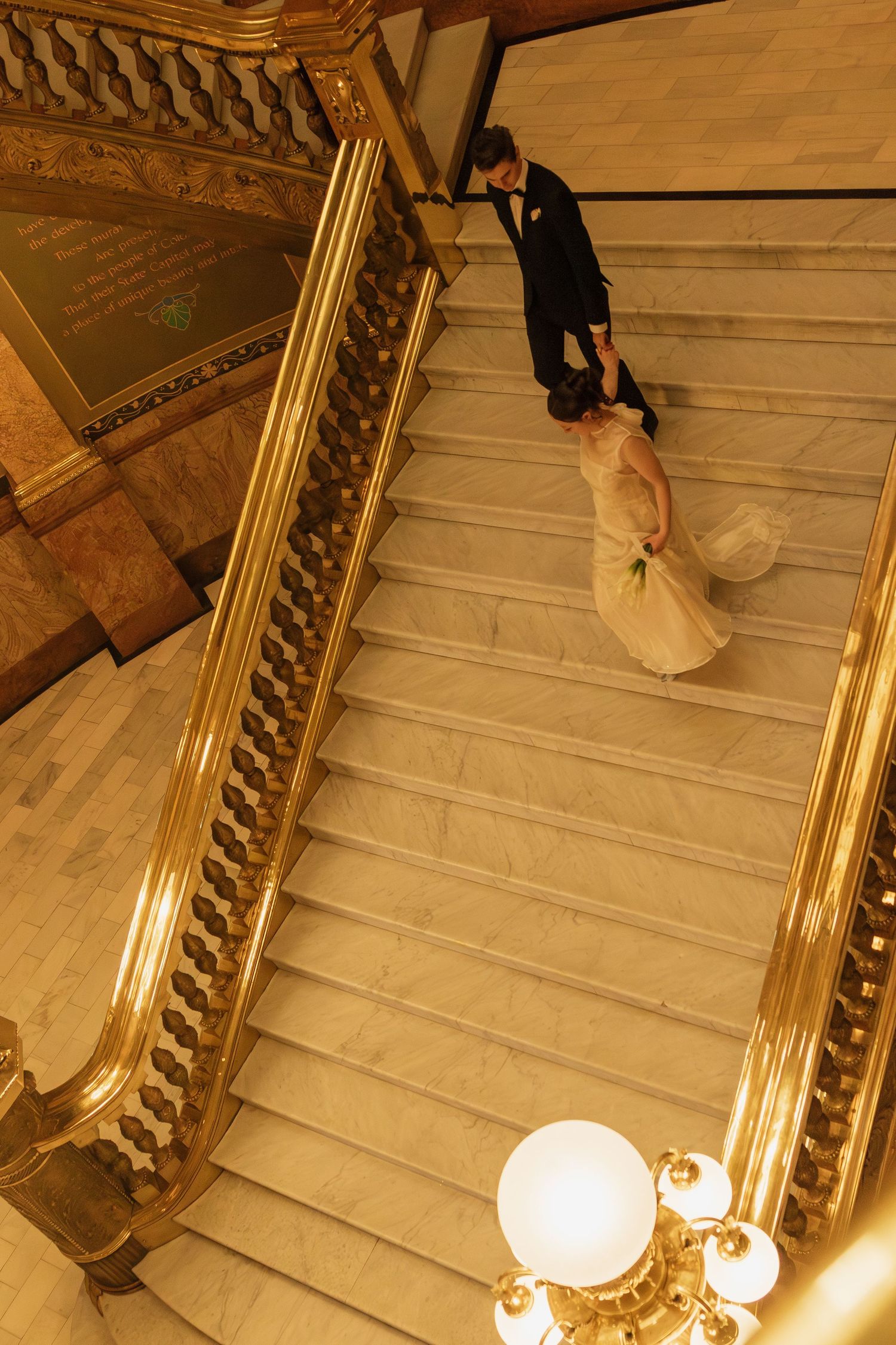 Elegant staircase with ornate gold railings and glowing globe lights in a grand historic building.