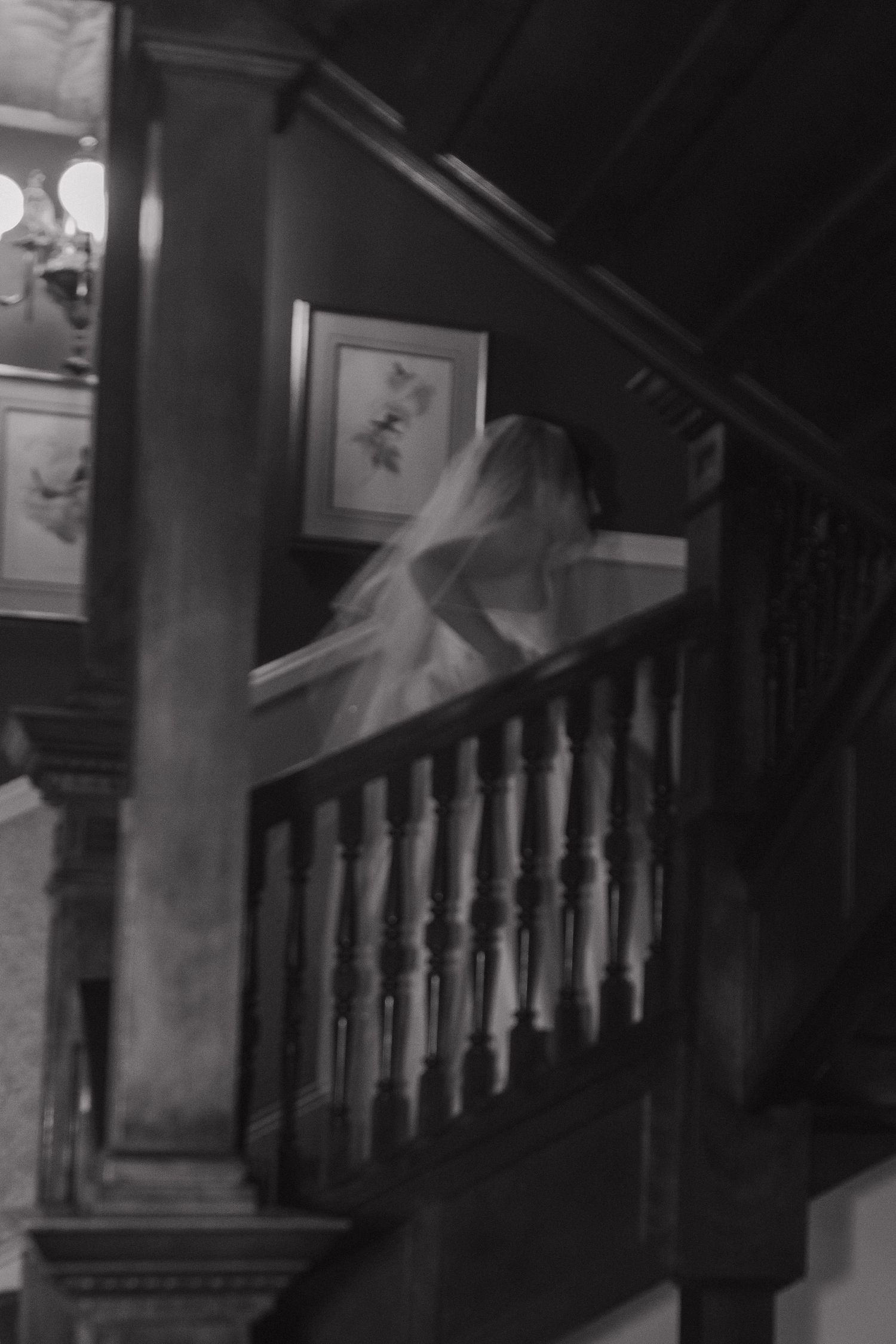 Dark and moody black and white photos of an old wooden staircase with ornate balusters in a dimly lit interior.