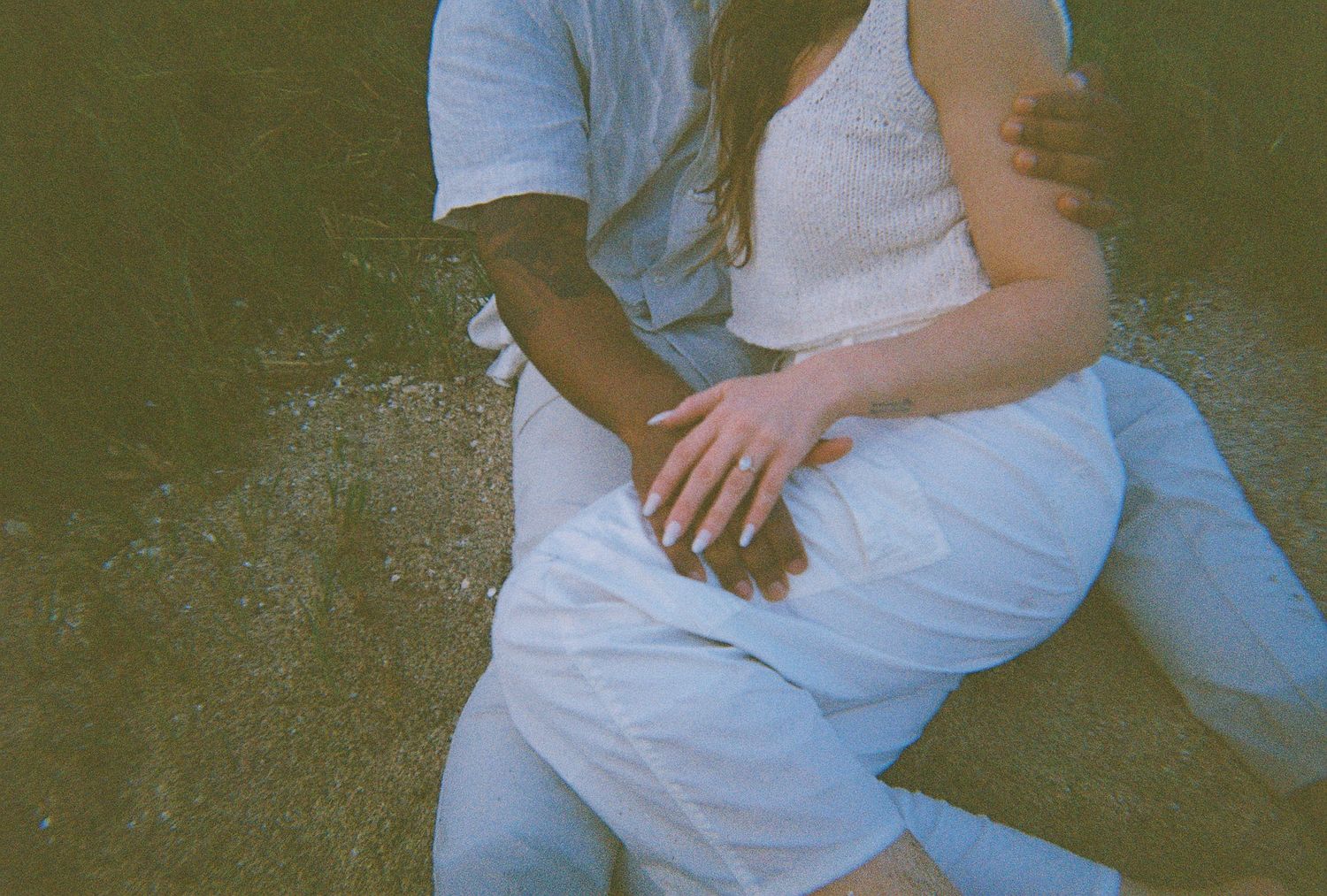People in white and blue clothing sitting together in a casual outdoor setting with a natural green background.