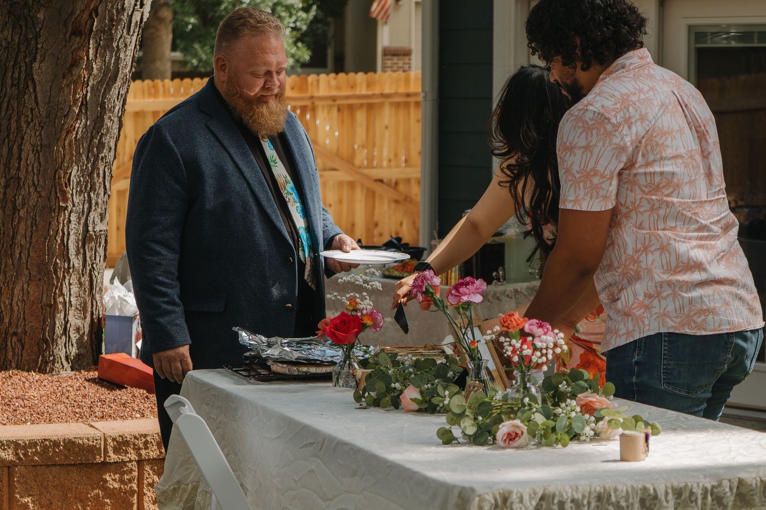 Elegant outdoor garden wedding reception with floral centerpieces and rustic wooden details.