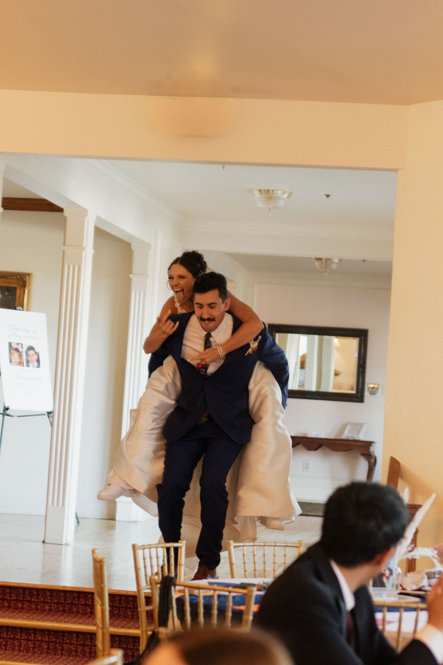 Playful moment during wedding reception in bright indoor venue.