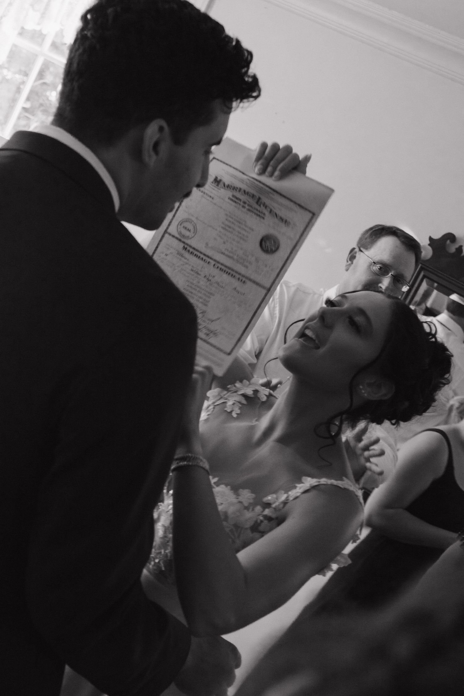 Wedding ceremony shot in black and white shows couple exchanging vows.