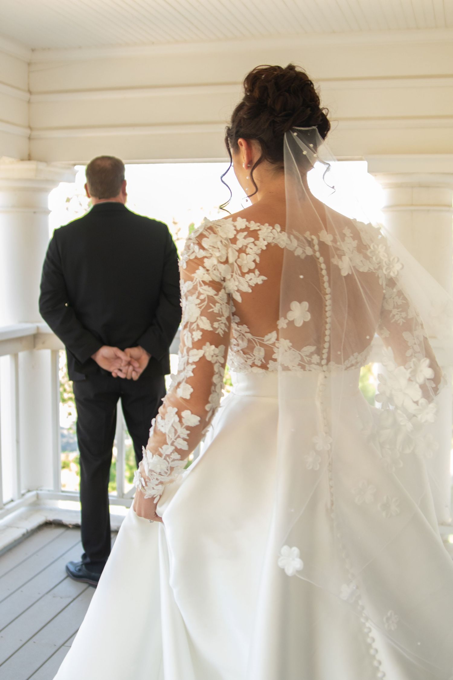 Detail shots of a white lace wedding gown and black suit on an elegant white porch.
