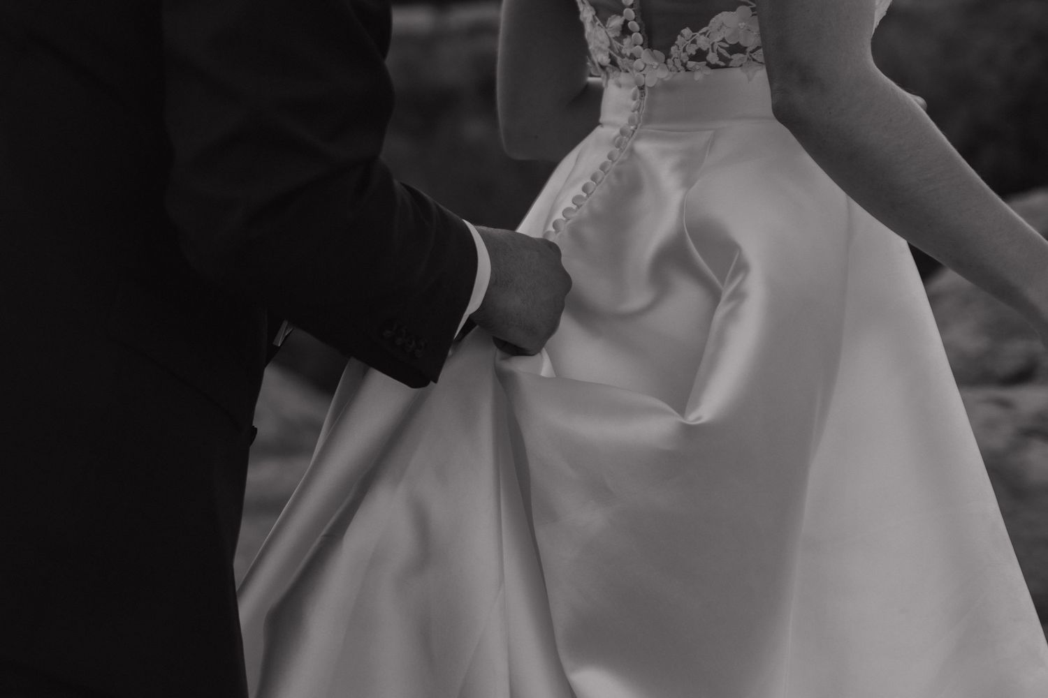 Elegant white wedding gown details captured in dramatic black and white photography.