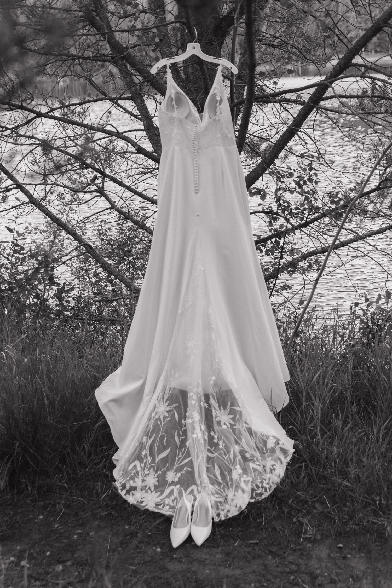 A sequence of photos showing the details of a white wedding dress with delicate lace trim hanging outdoors against trees.