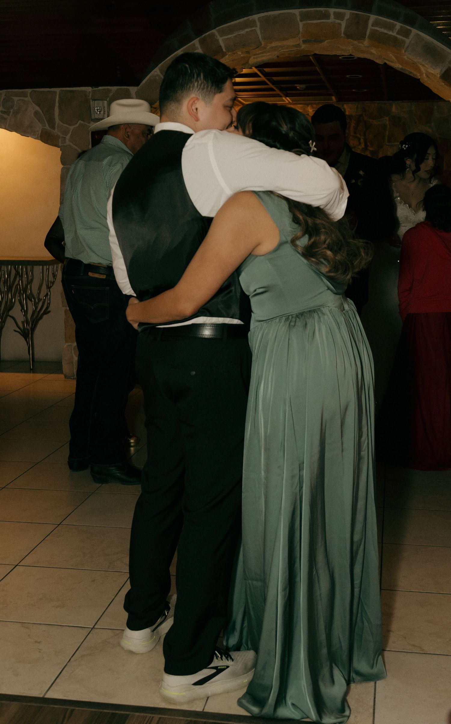Couple sharing a romantic dance embrace at a wedding reception in sage green gown.