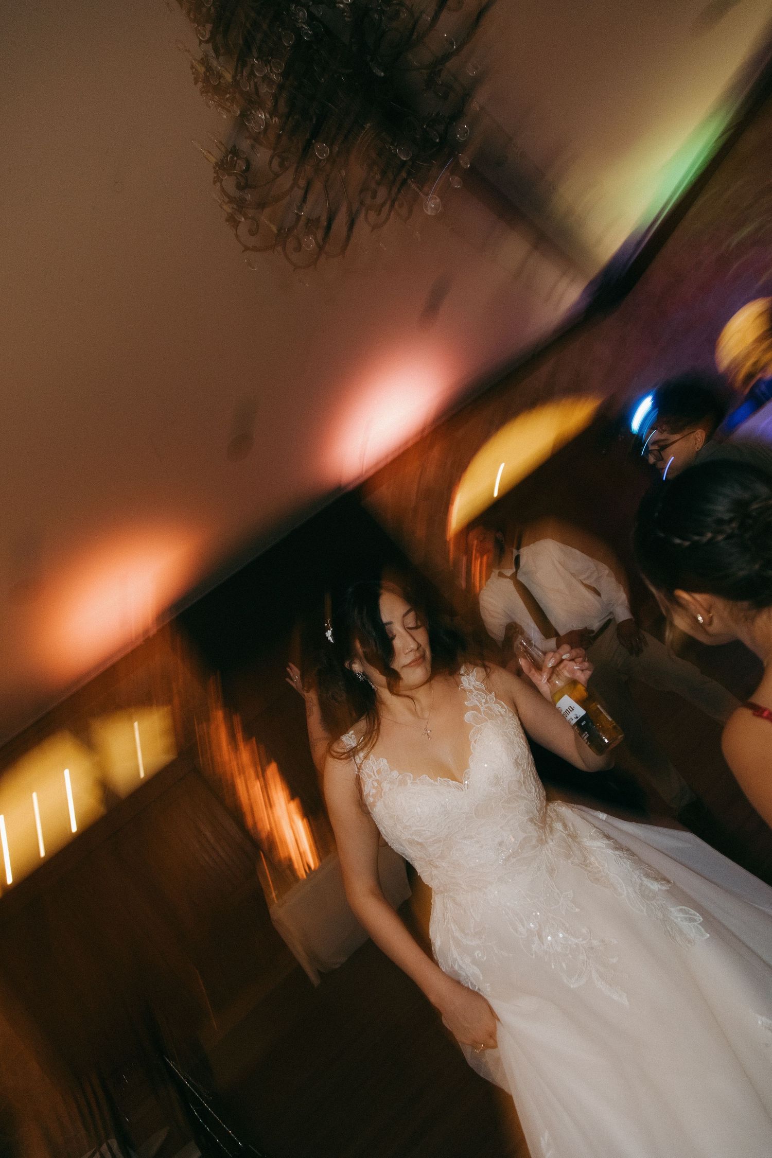 Bride in lace wedding gown dancing with motion blur effect at reception.