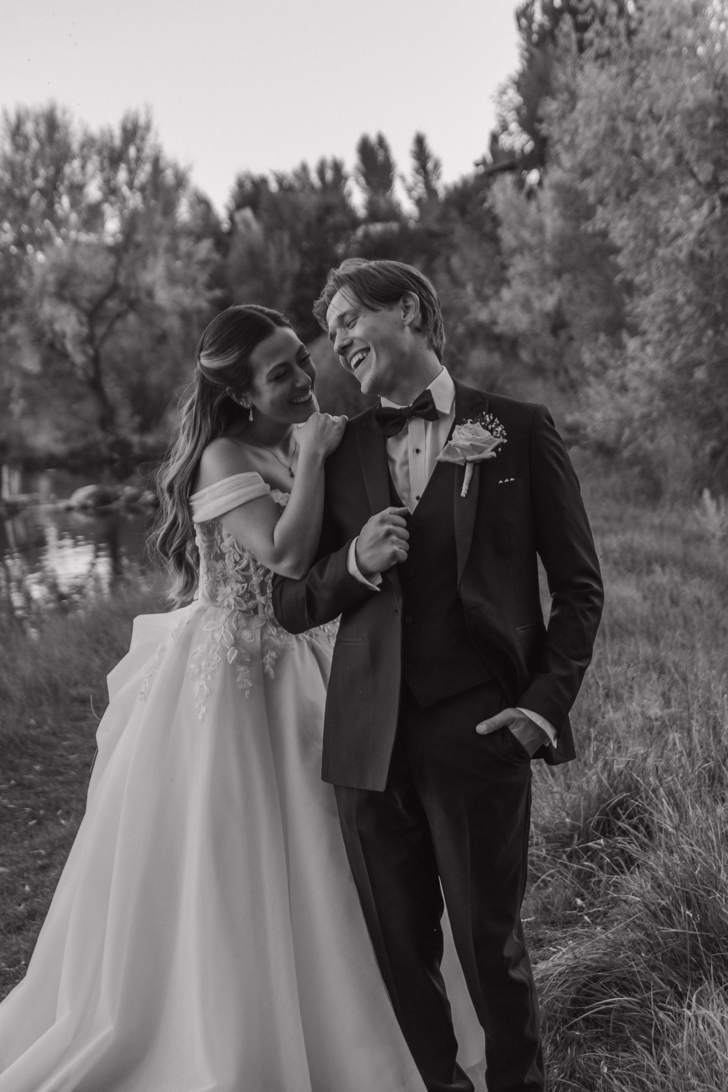 Black and white wedding photos show a couple sharing joyful moments together outdoors in a natural setting.