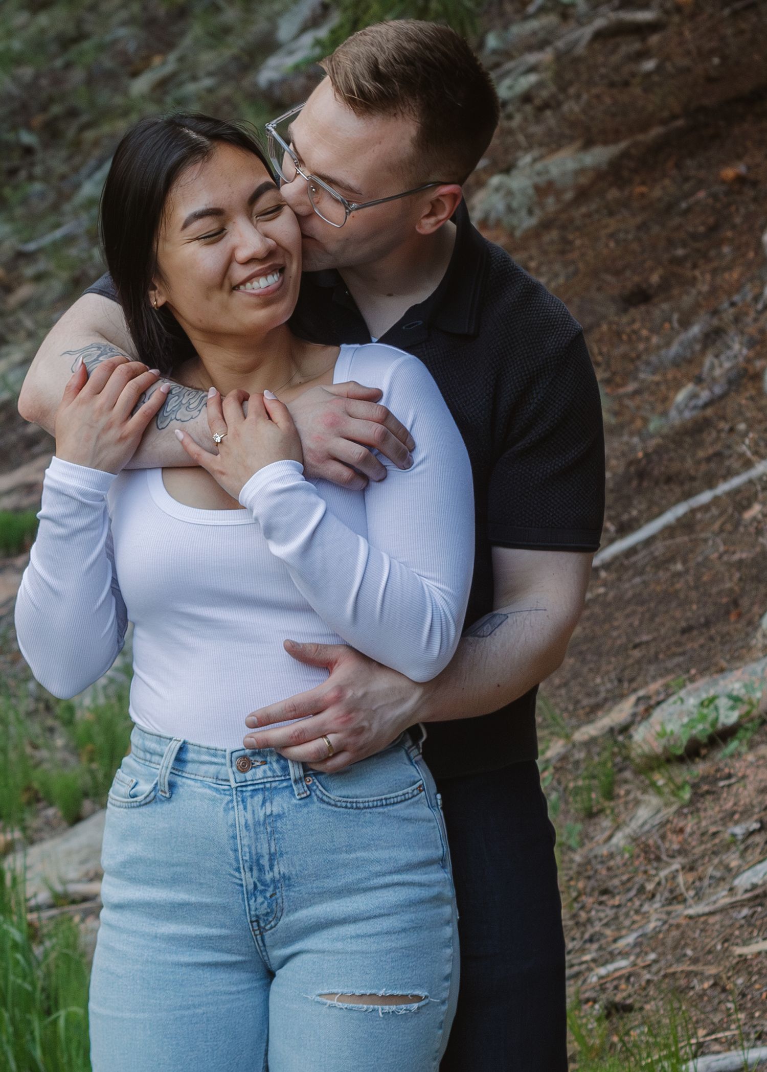A candid moment of laughter and affection captured against a natural forest backdrop.
