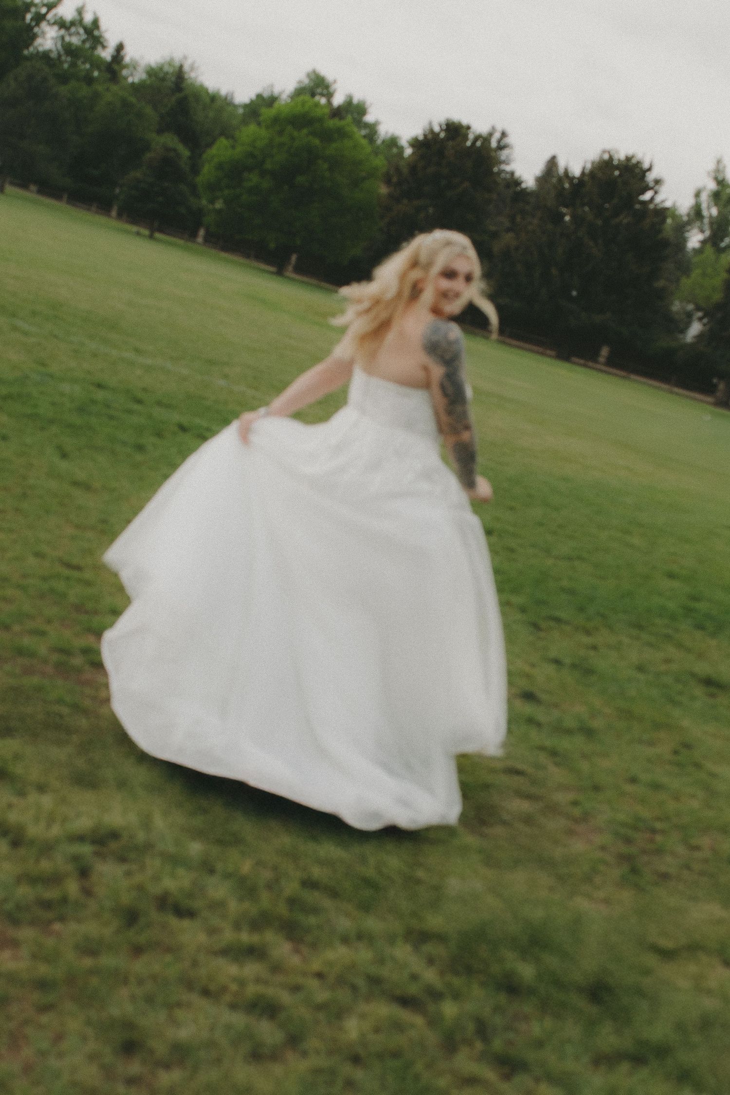 White wedding dress spins dramatically across a green outdoor field.