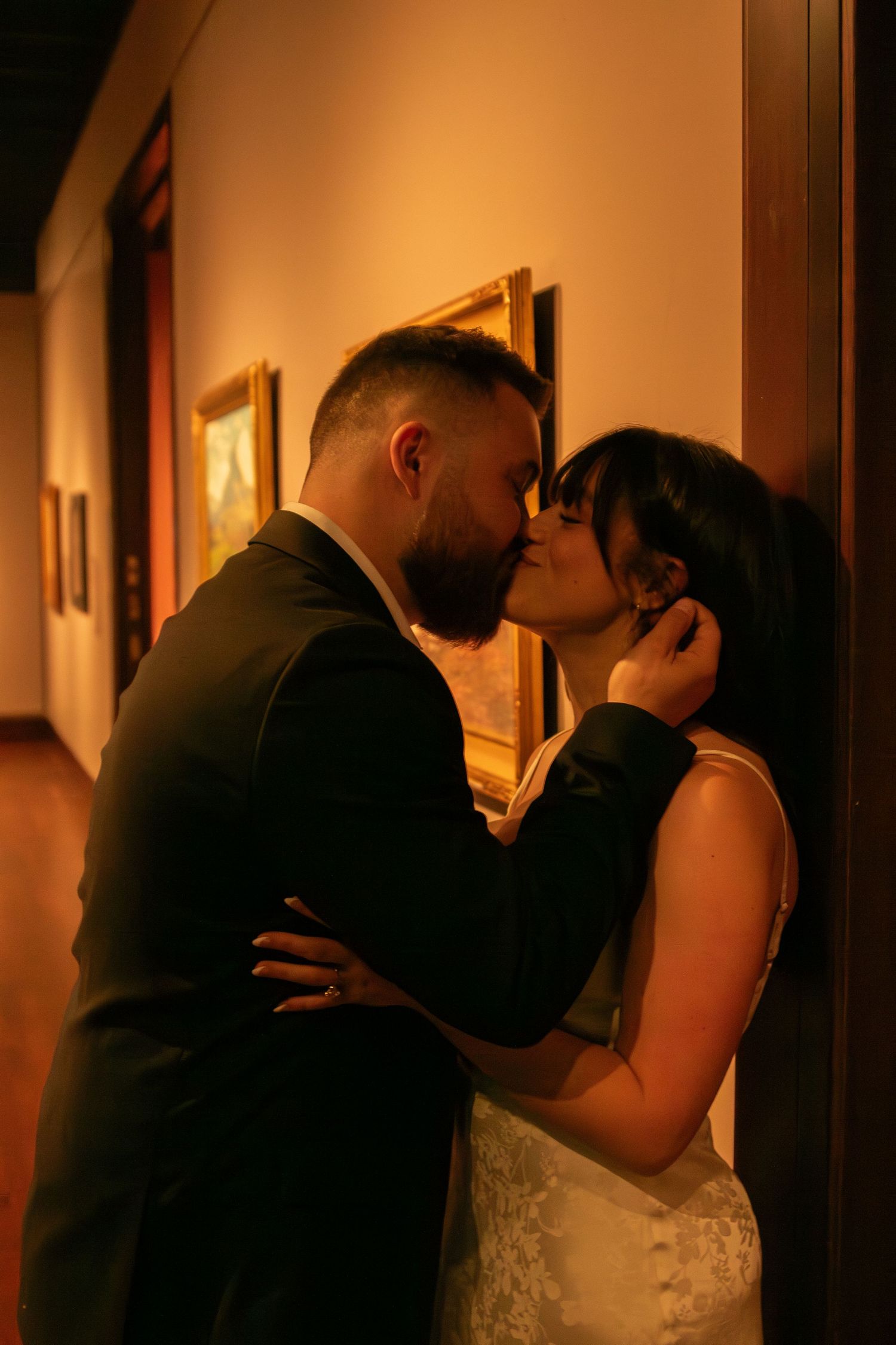 An intimate moment captured in warm lighting within an art gallery hallway.