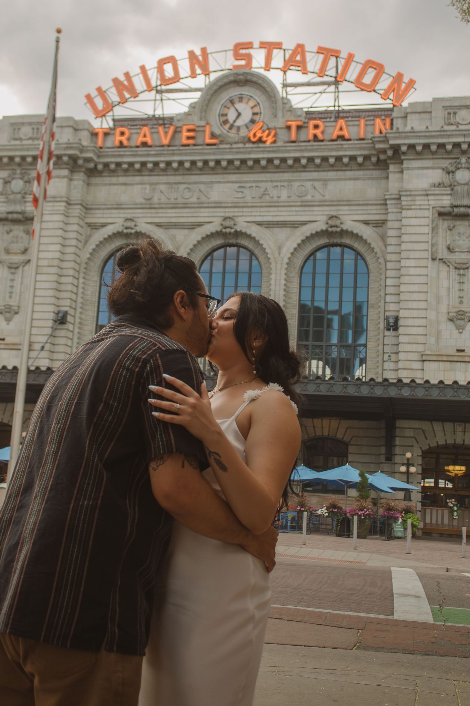 A couple embraces in a romantic kiss outside Denver's historic Union Station building.