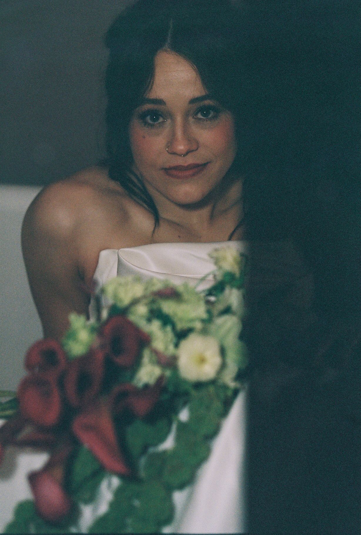 Wedding bouquet with deep red roses and cream flowers against white dress.
