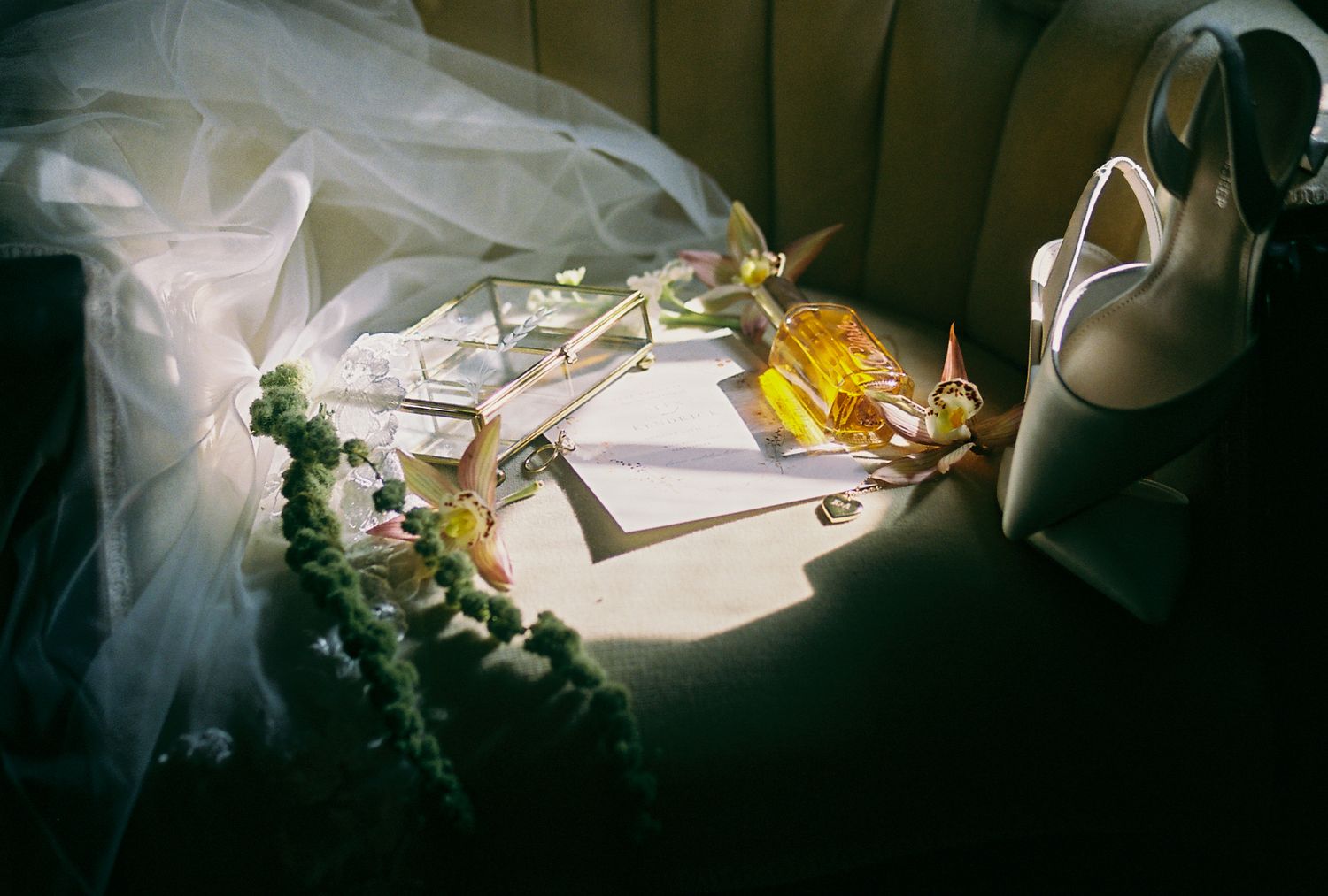 Artistic detail shot of wedding dress and accessories in moody lighting.