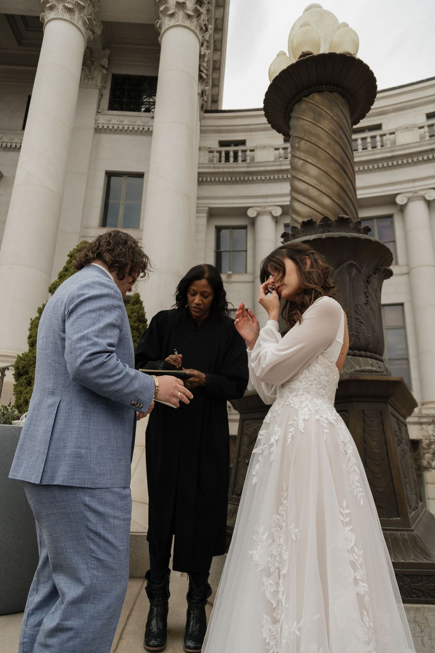 A couple shares their first dance as newlyweds in front of a grand columned building with classical architecture.
