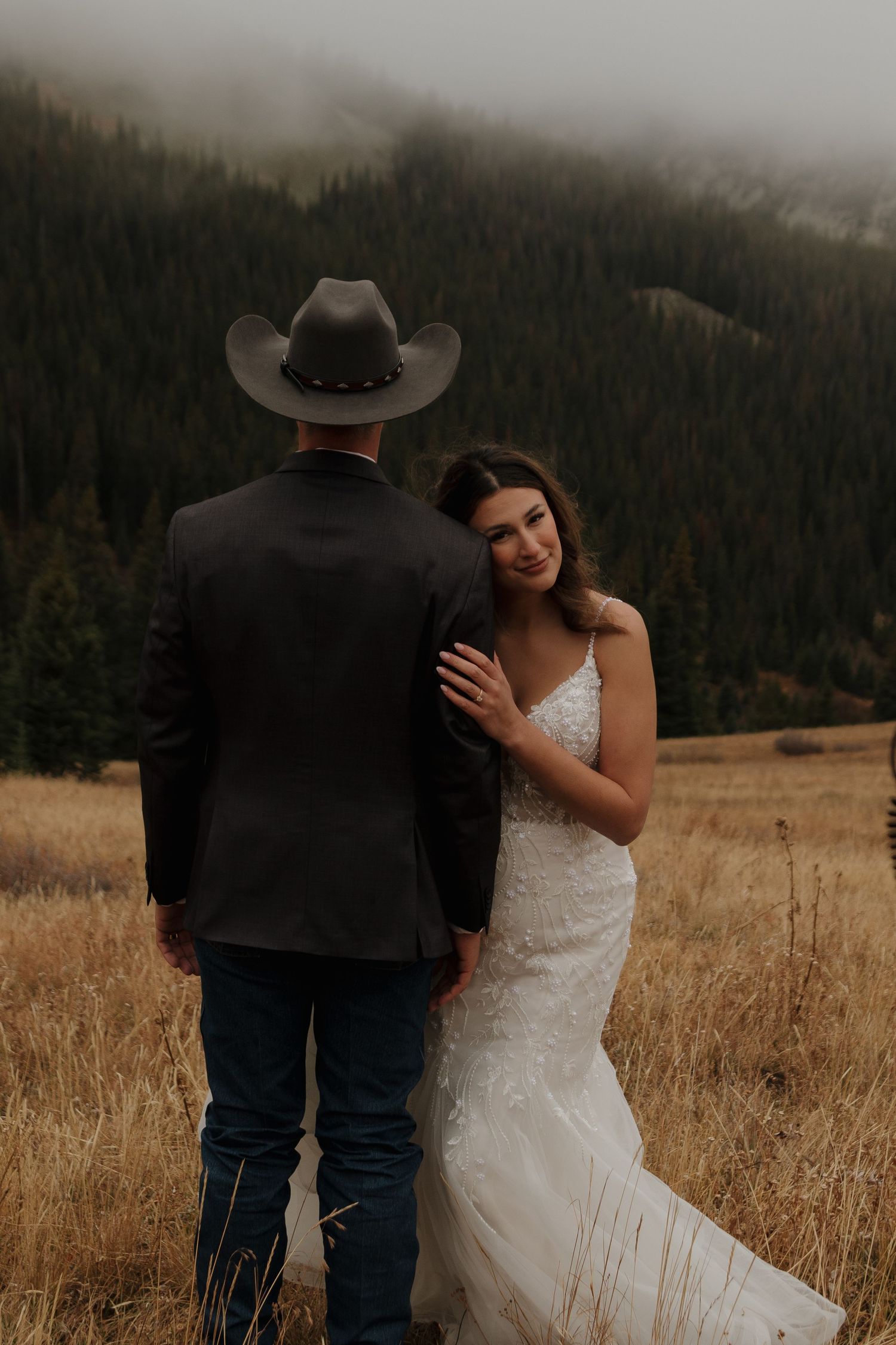 A couple shares an intimate moment in a mountain meadow during golden hour.