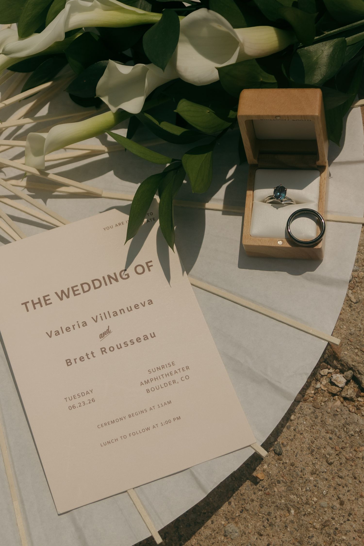 Wedding invitation for Valeria Villanueva and Brett Rousseau with rings and white calla lilies.