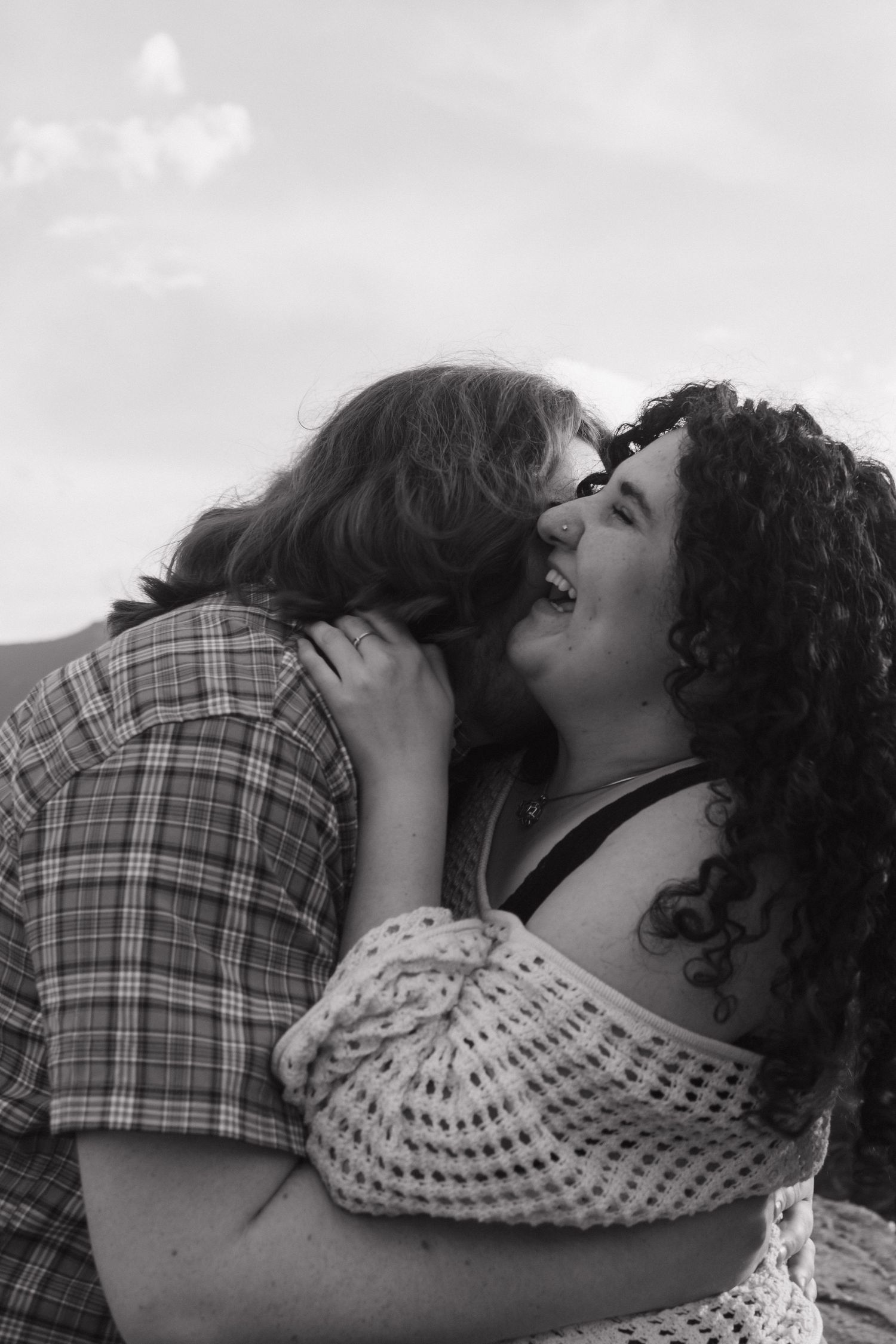 A romantic embrace captured in black and white with mountains in the background.