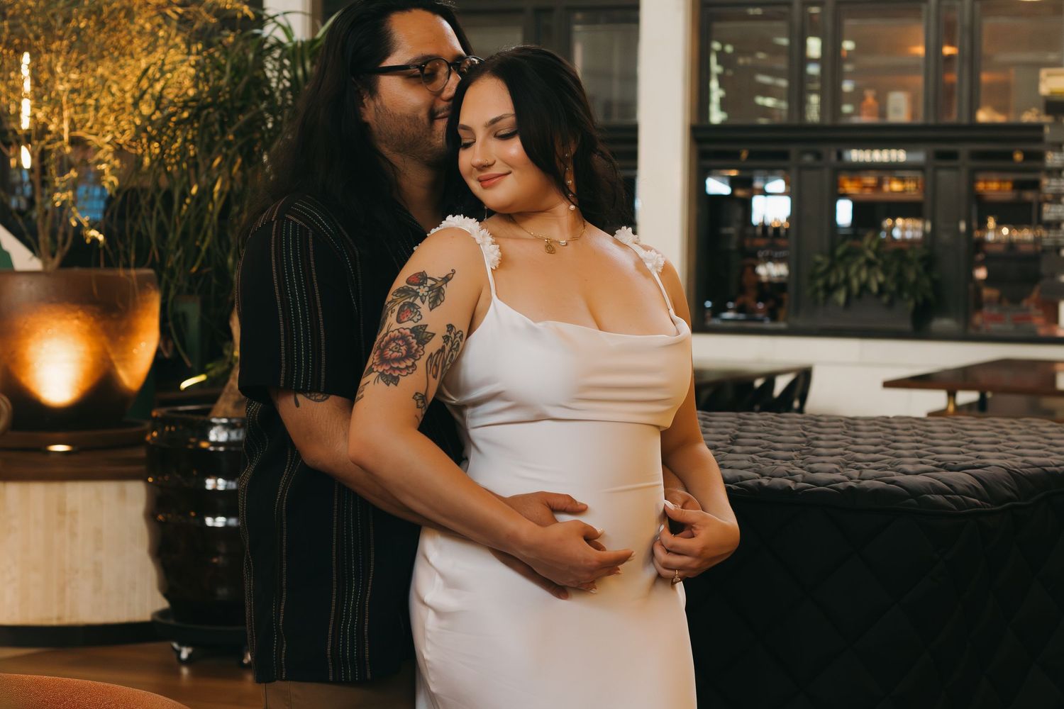 A tender moment captured between a couple in formal attire at an indoor venue with ambient lighting.