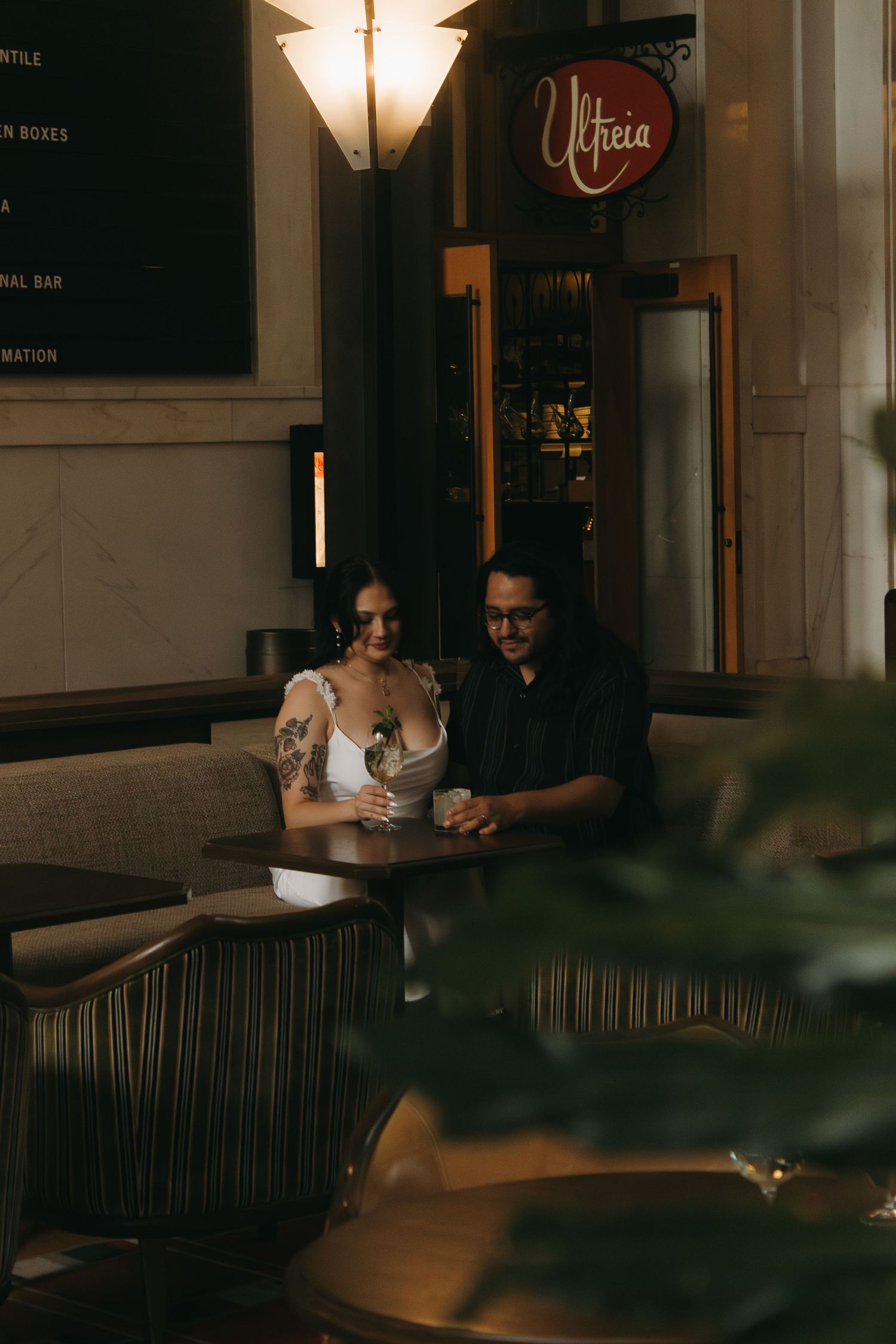 A couple sits together at a dimly lit restaurant table with warm ambient lighting creating an intimate atmosphere.