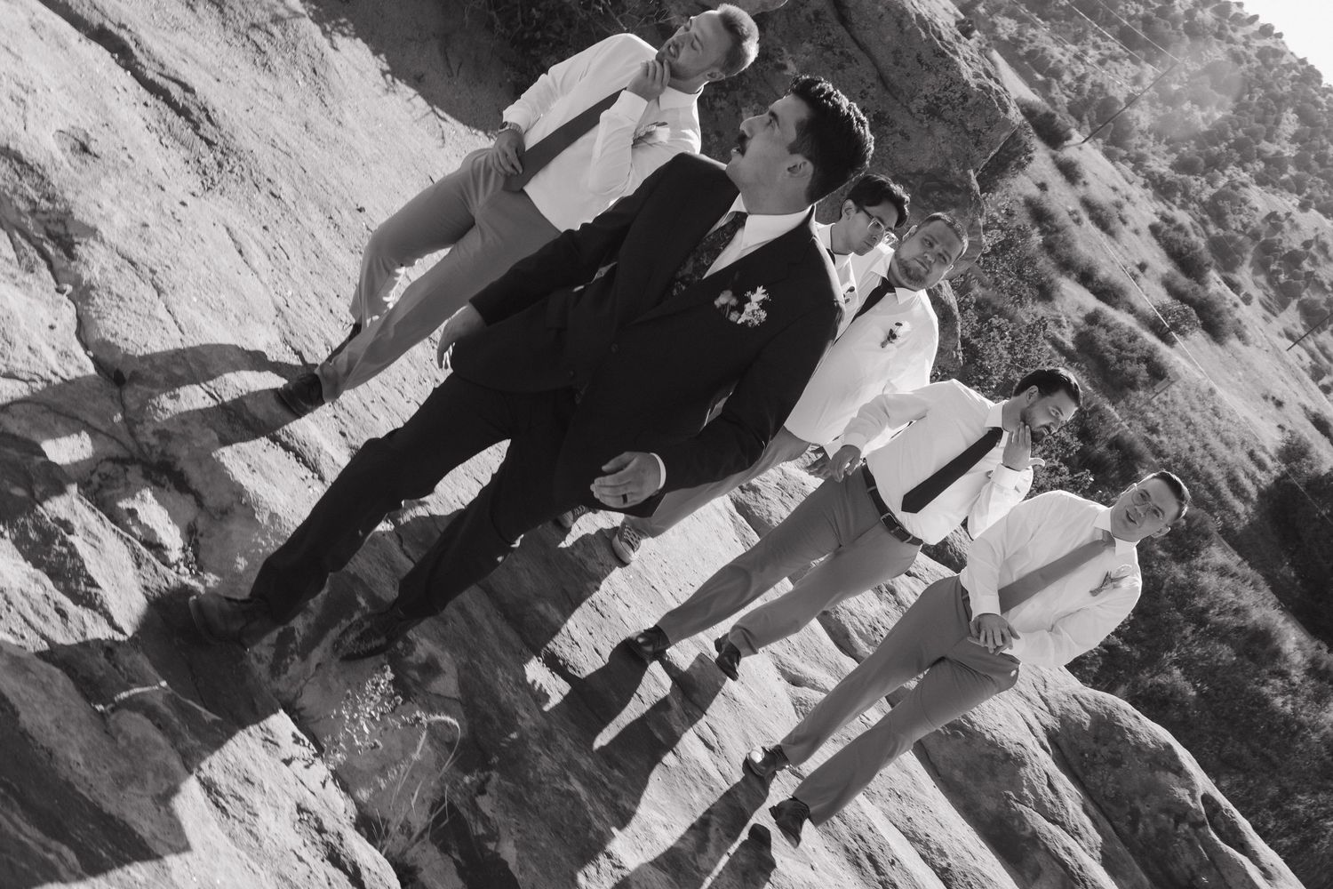 Black and white group portrait of wedding party on rocky mountain terrain.