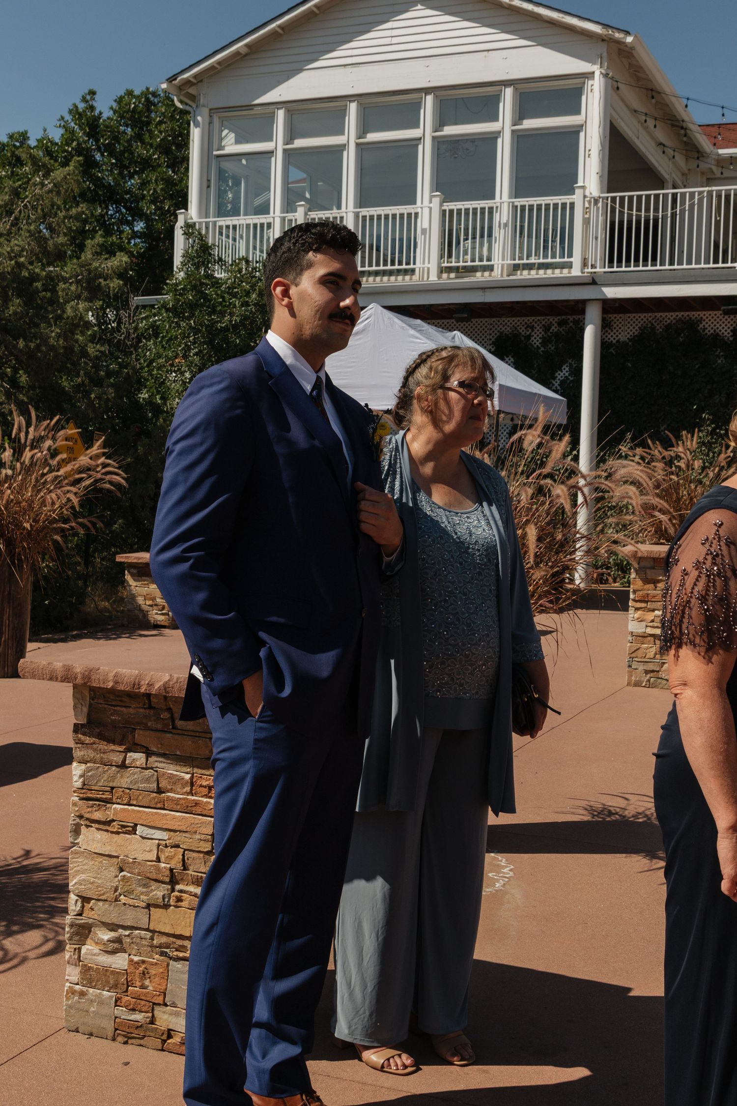 A series of candid moments between guests at an outdoor venue with a white house in the background.