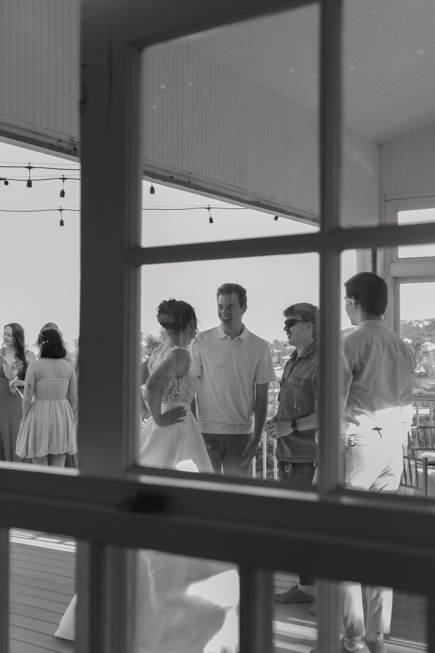 Black and white silhouettes of wedding guests through window panes.