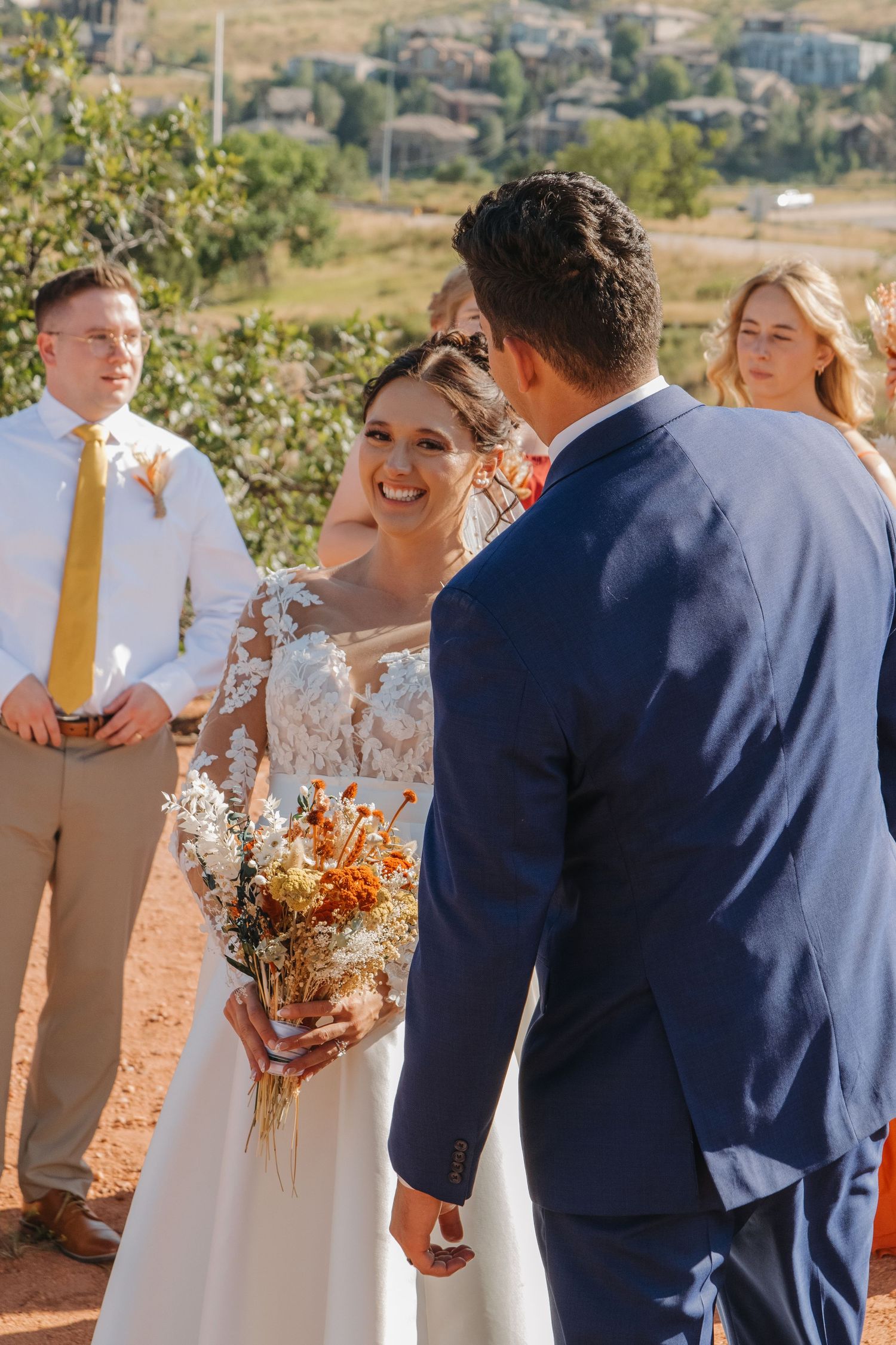 Wedding ceremony participants gather outdoors with dried flower bouquets.