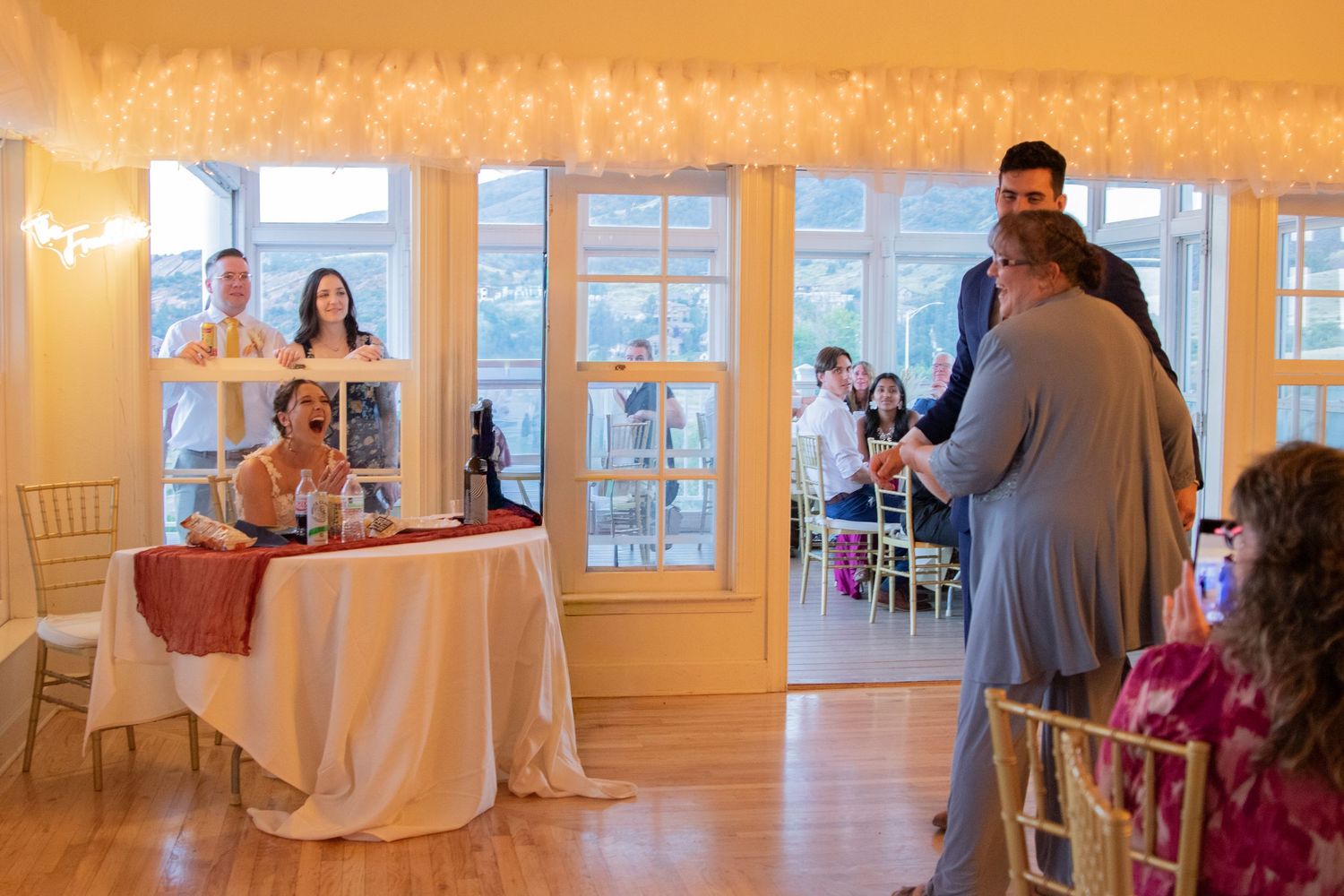 Warm-toned panoramic view of an elegant wedding reception venue with large windows.