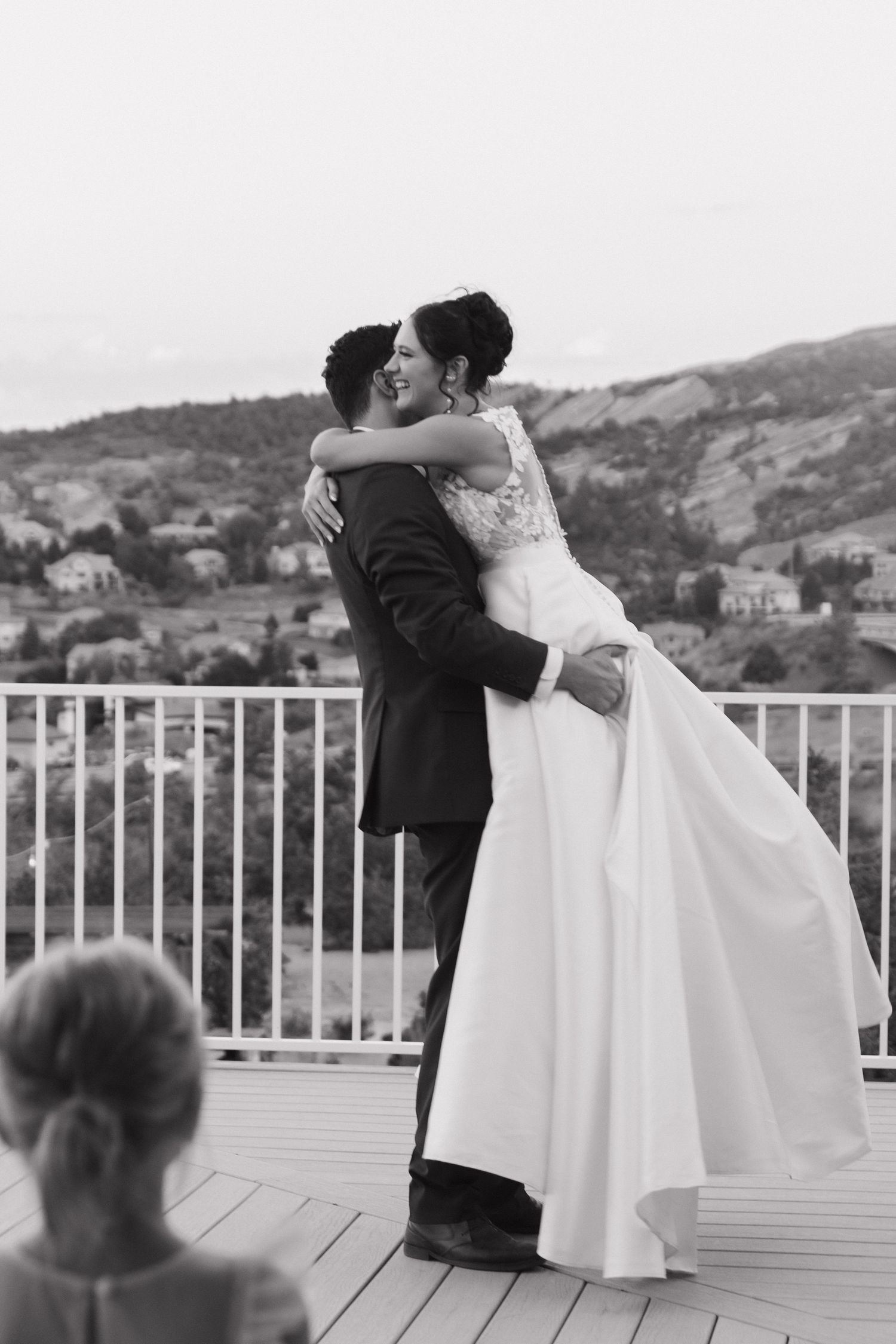 Couple sharing a dance on a deck overlooking a scenic hillside landscape.