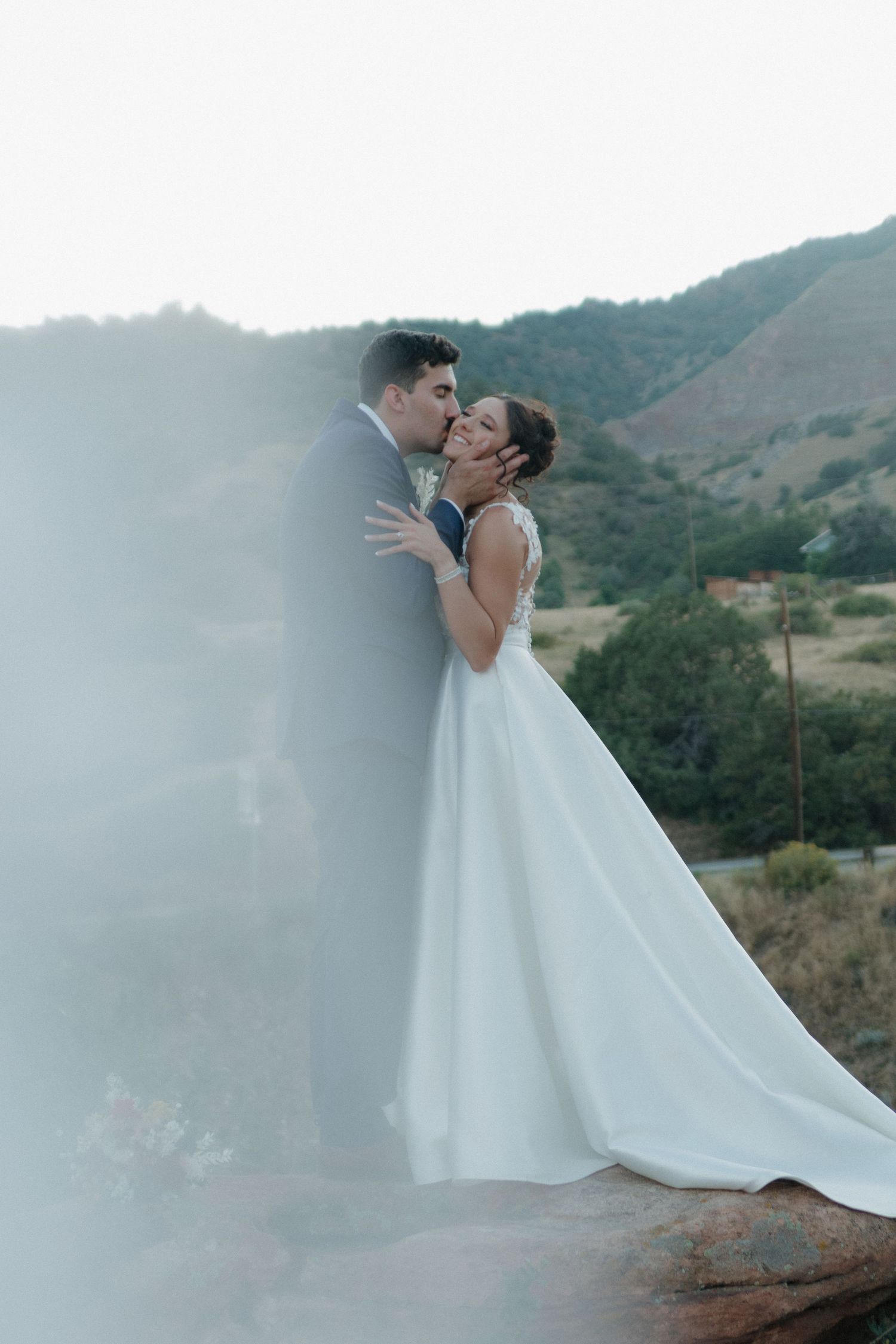 Artistic wedding photos with dramatic mountain backdrop and flowing white dress.