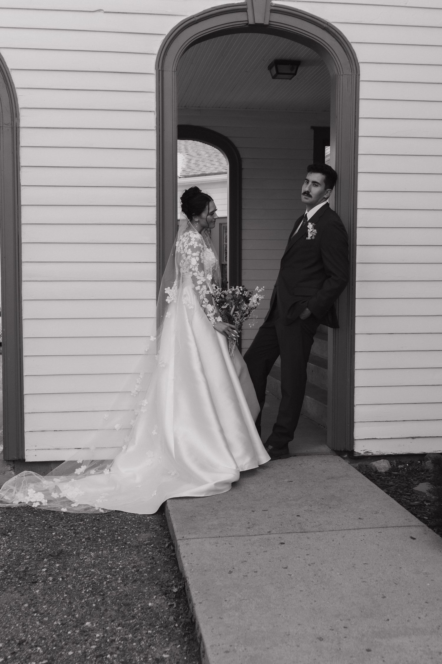 Wedding party entering white church entrance with grand doorways.